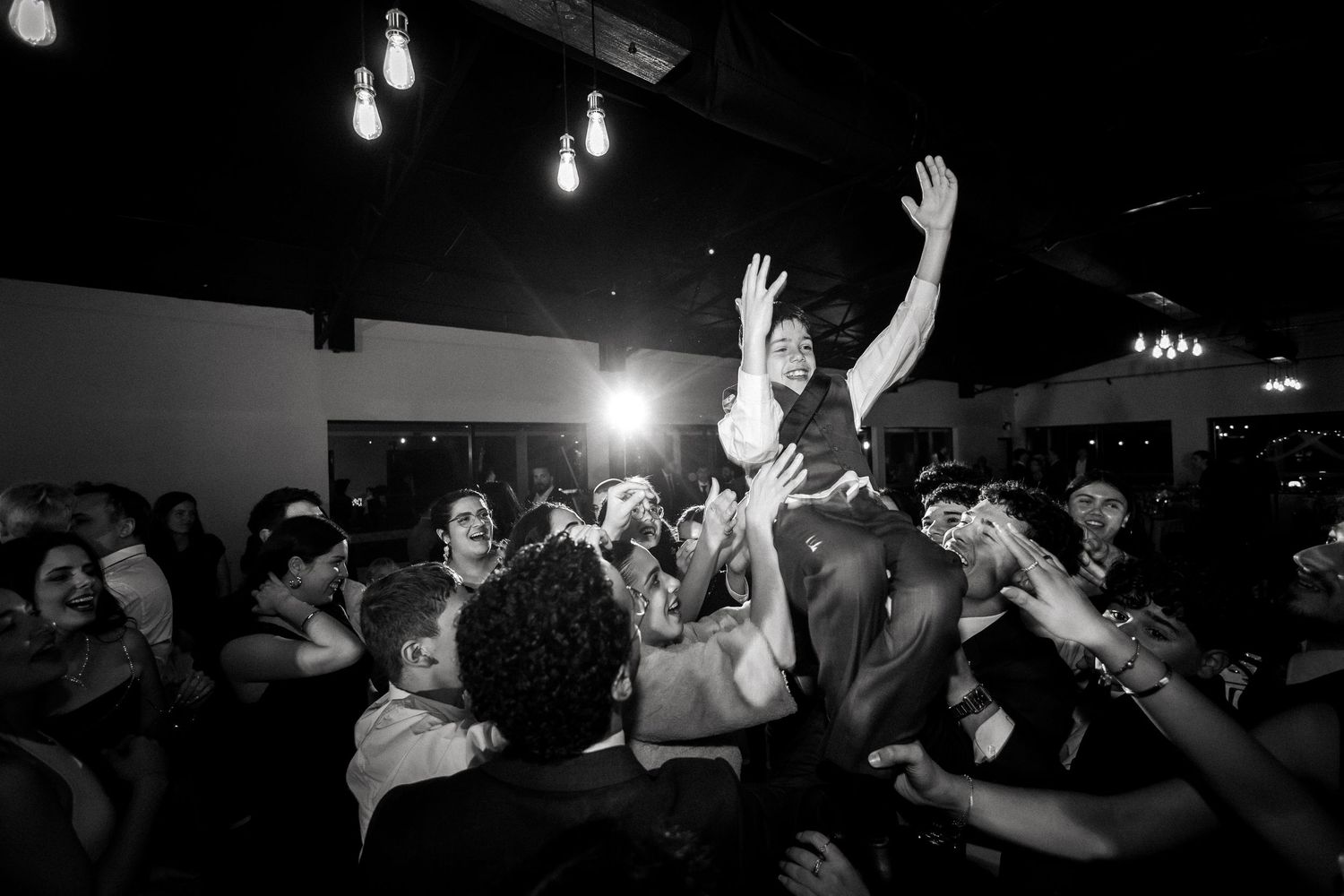 Energetic wedding guest crowd surfs at a lively black and white reception party.