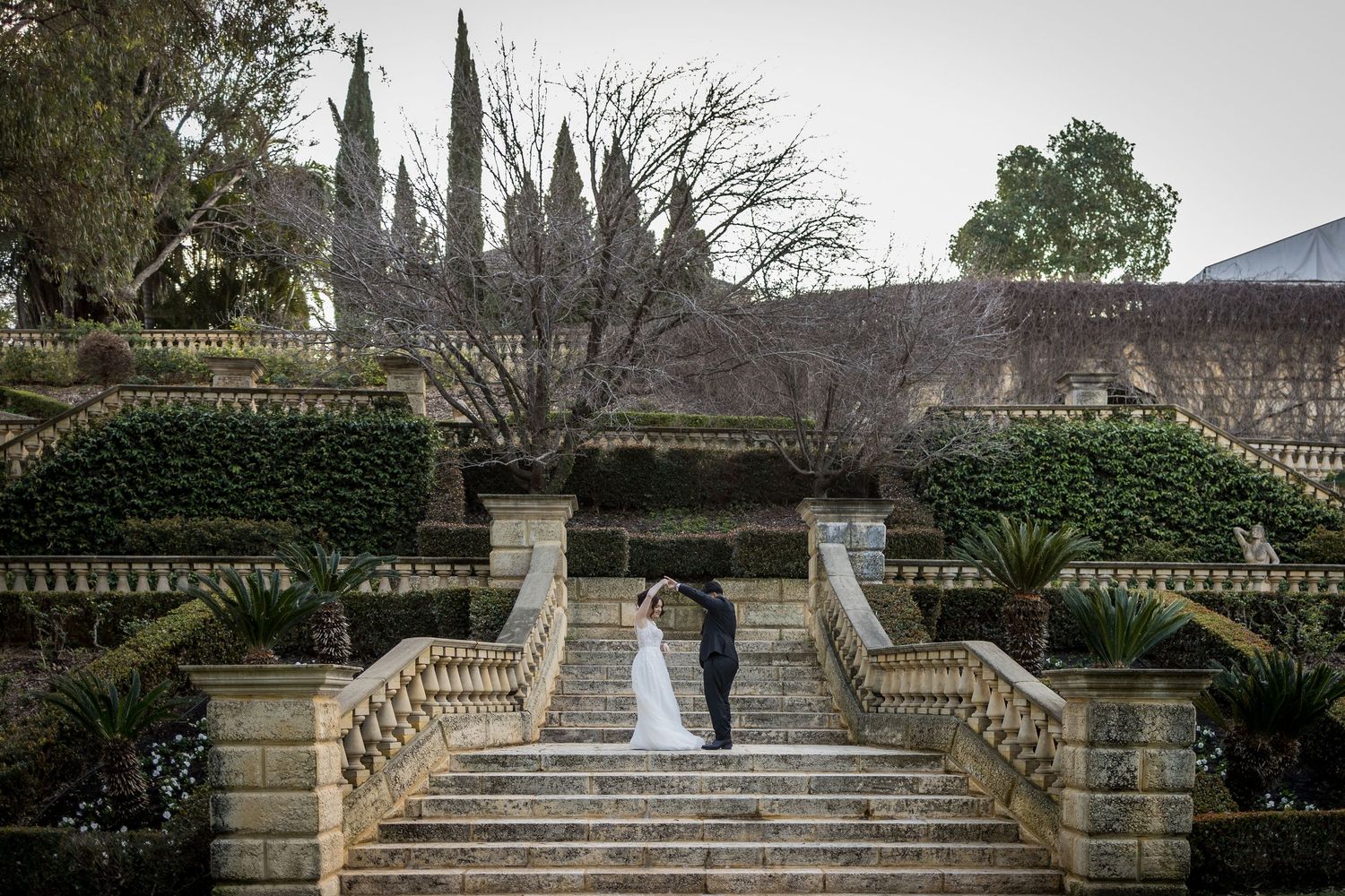 Grand stone staircase with classical balusters leads up through a formal garden setting.