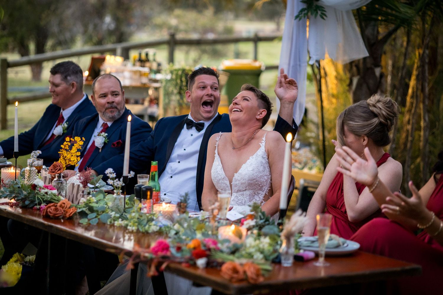Wedding reception guests enjoying dinner and conversation at decorated outdoor tables.