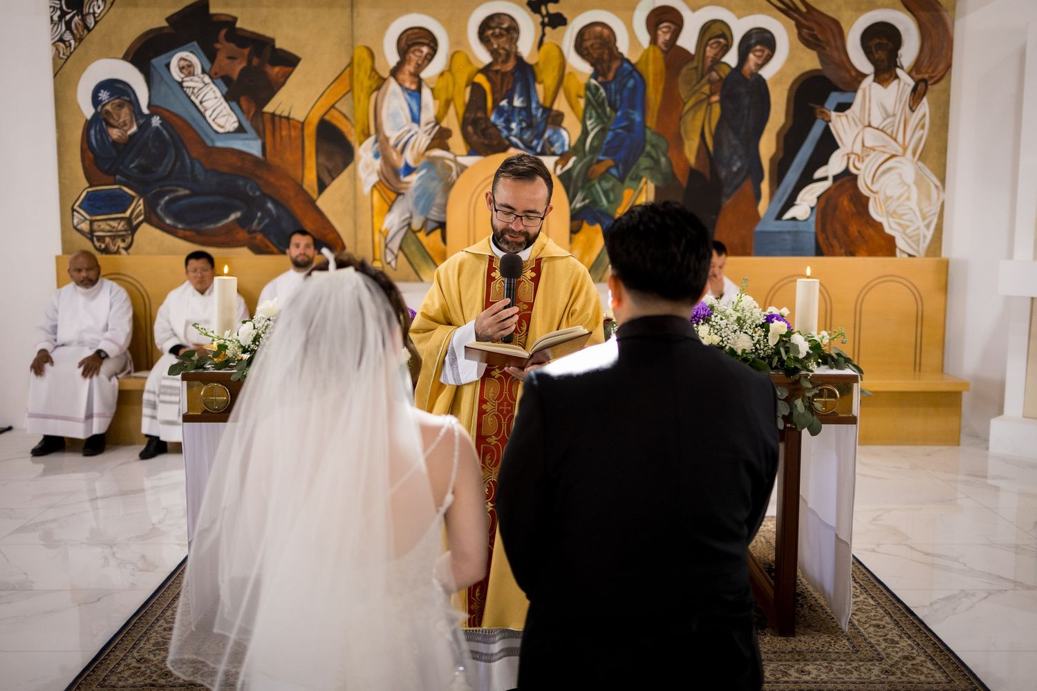 Religious icons and artwork adorn the walls of an ornate church during a wedding ceremony.