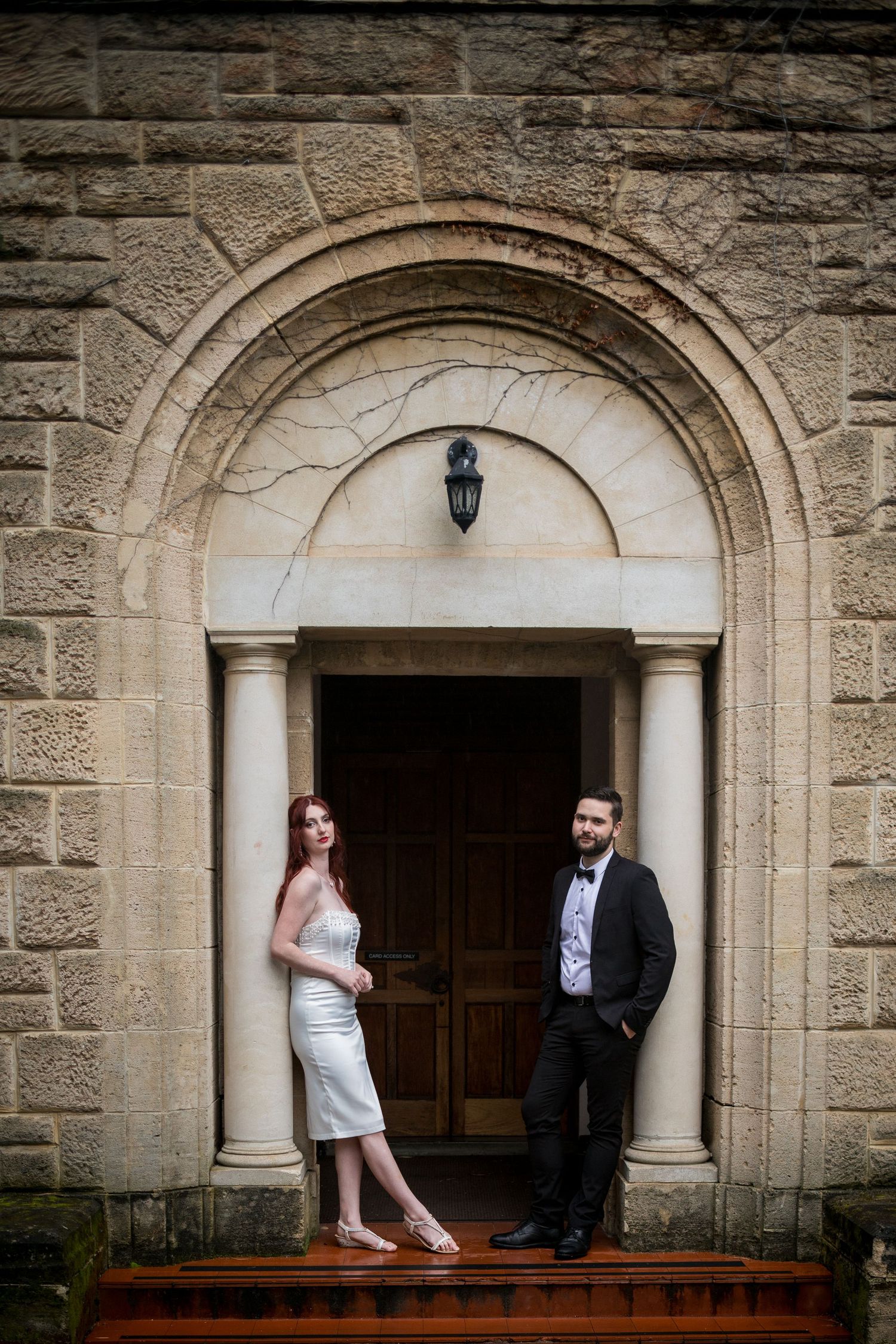 Couple poses in arched stone doorway of historic building.
