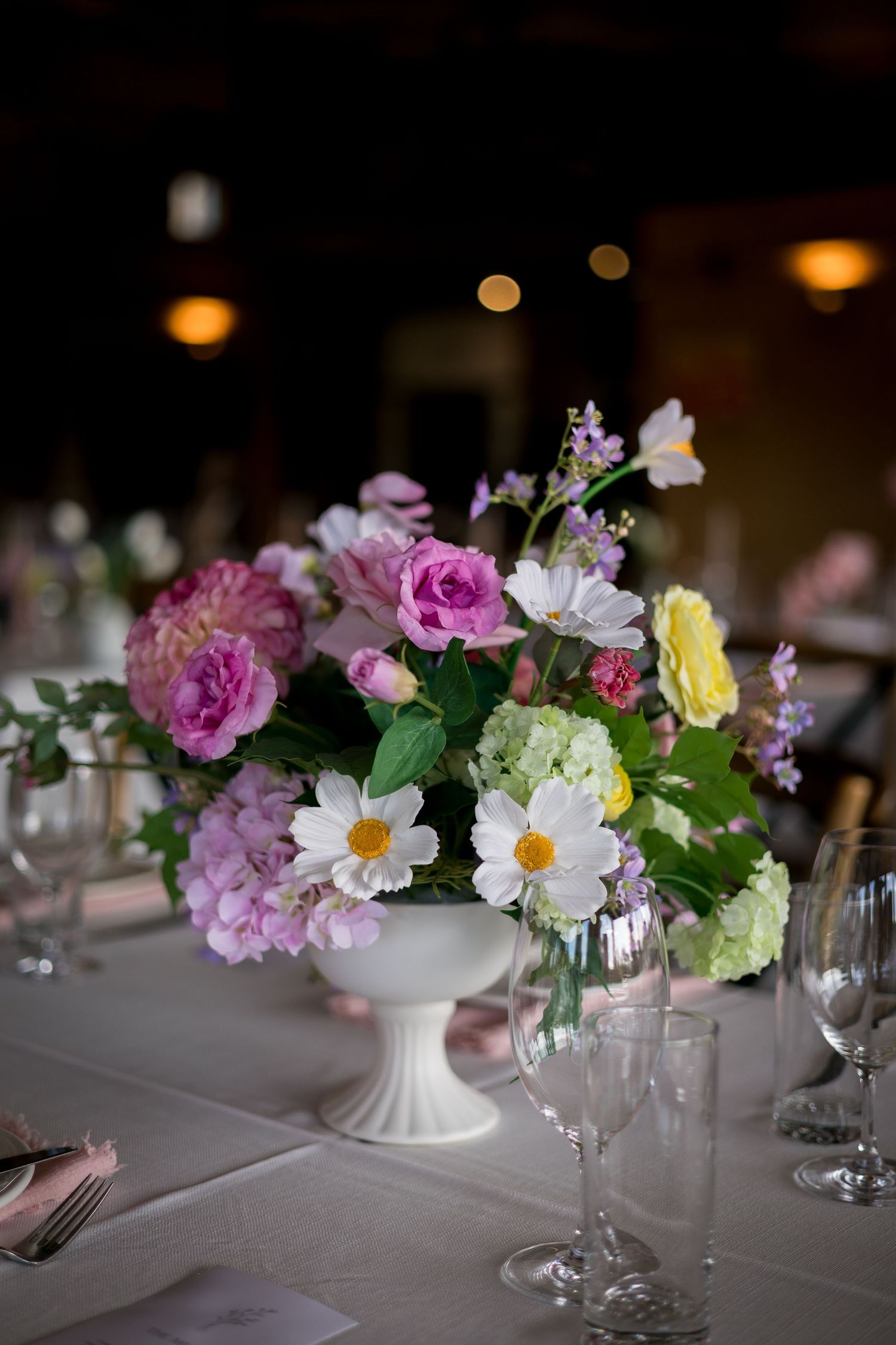 Colorful spring flower arrangements in white vases adorn a formal dining table.