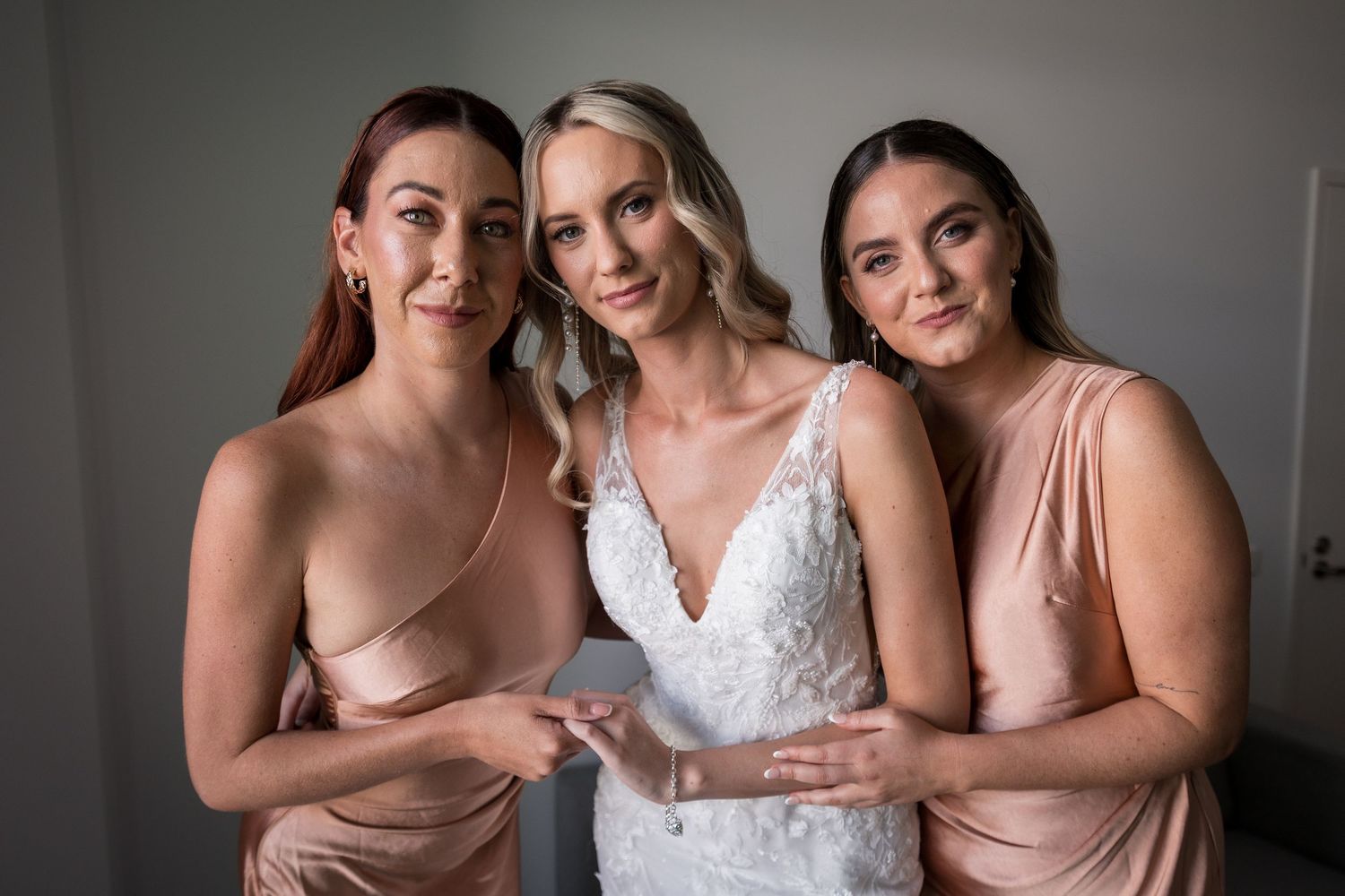 Bridesmaids in blush dresses pose together during wedding celebrations.