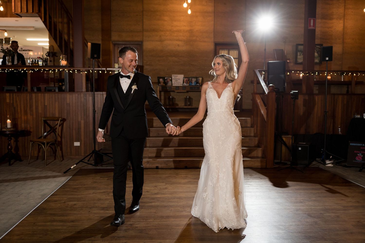 Couple dances in rustic wooden barn venue with string lights.