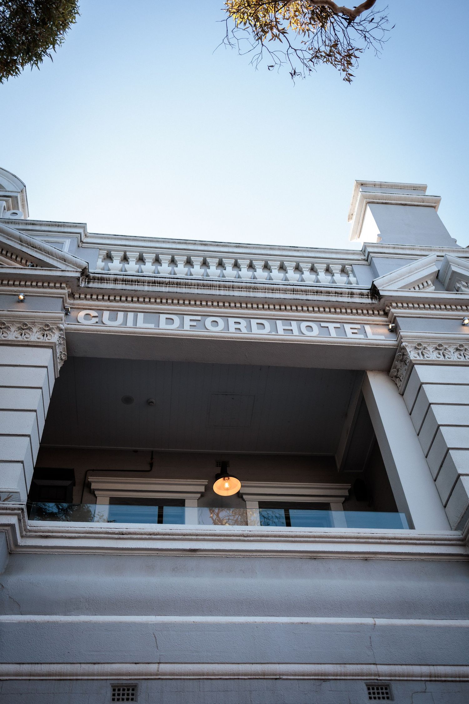 Low-angle view of the historic Guildford Hotel facade, featuring ornate white architecture and decorative detailing.