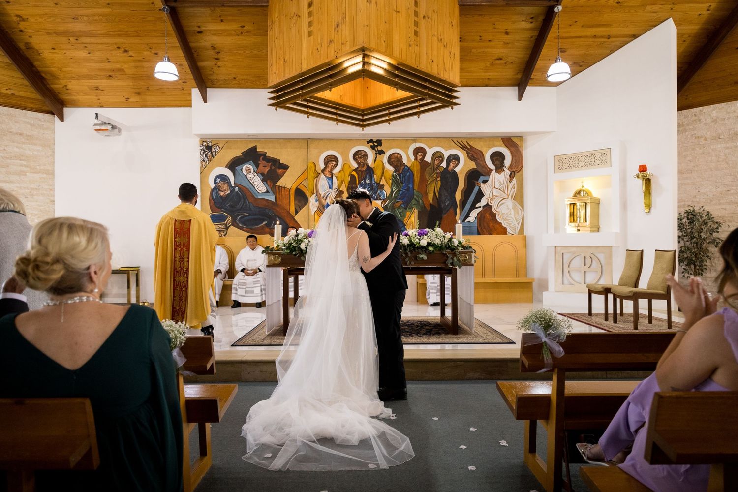 Church interior with wooden beams and white walls during a wedding ceremony.
