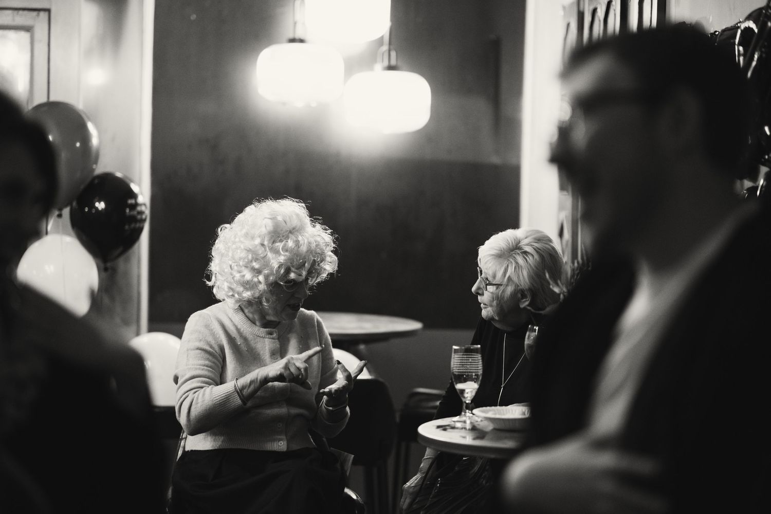 A series of black and white photos showing people gathered in a dimly lit bar or restaurant setting.