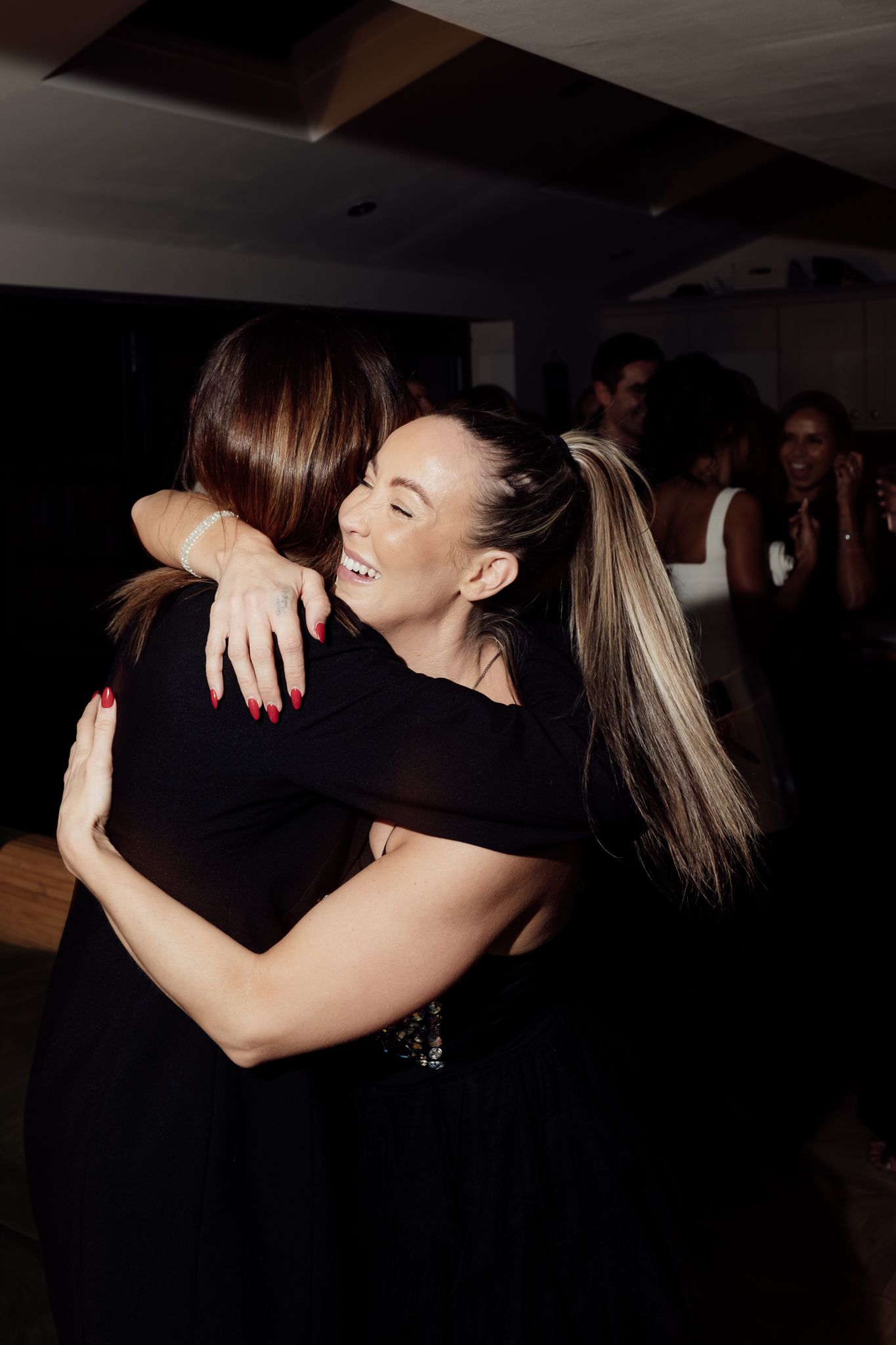 People embracing during an emotional moment at a dimly lit party.