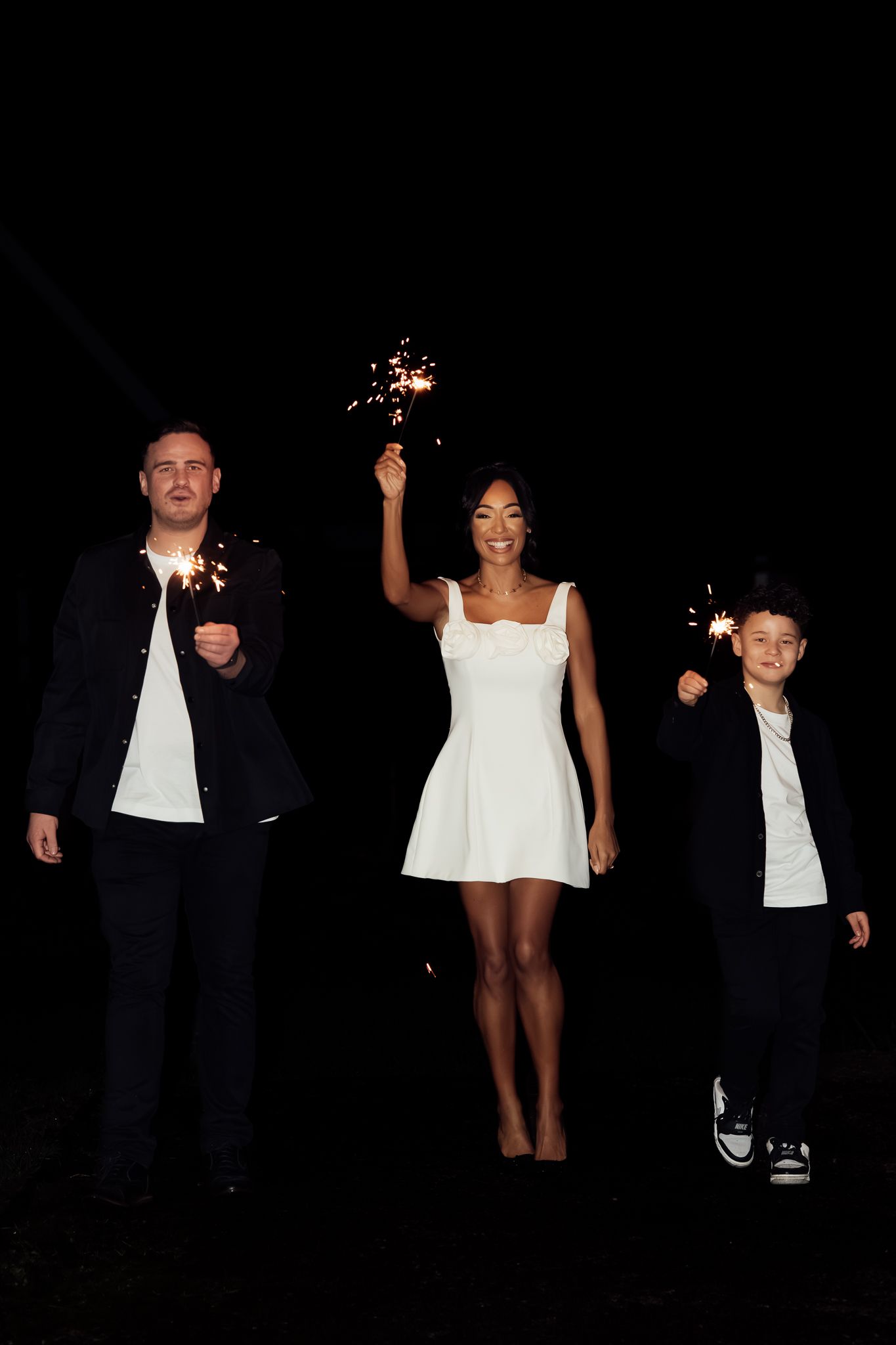 Group of people walking through a dark space with sparklers creating light trails.