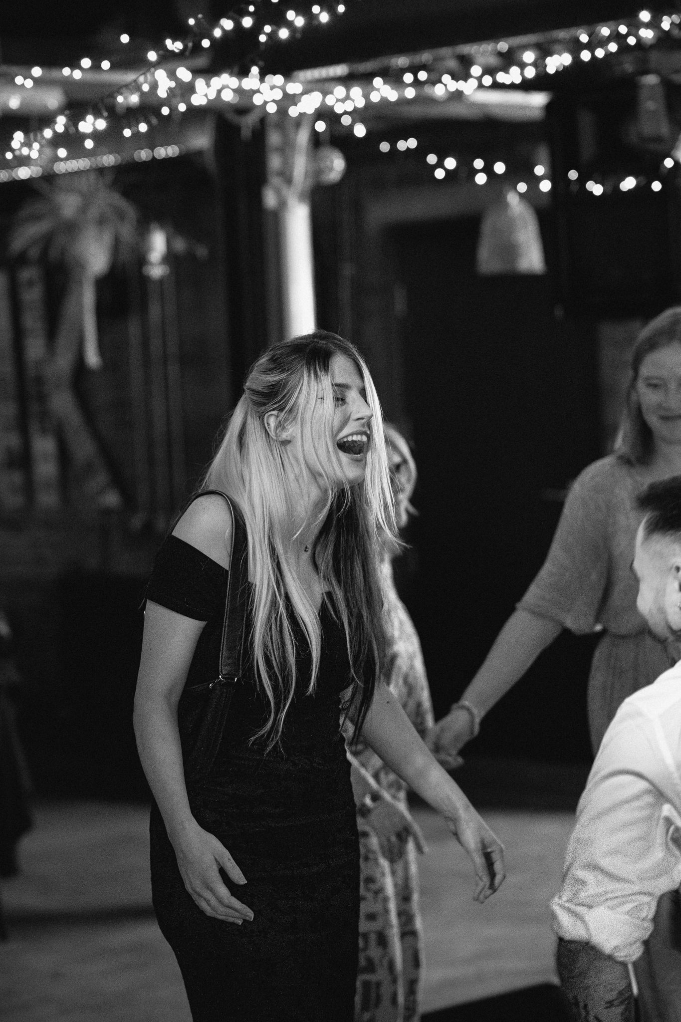 Blonde woman laughing and dancing joyfully at wedding reception party.