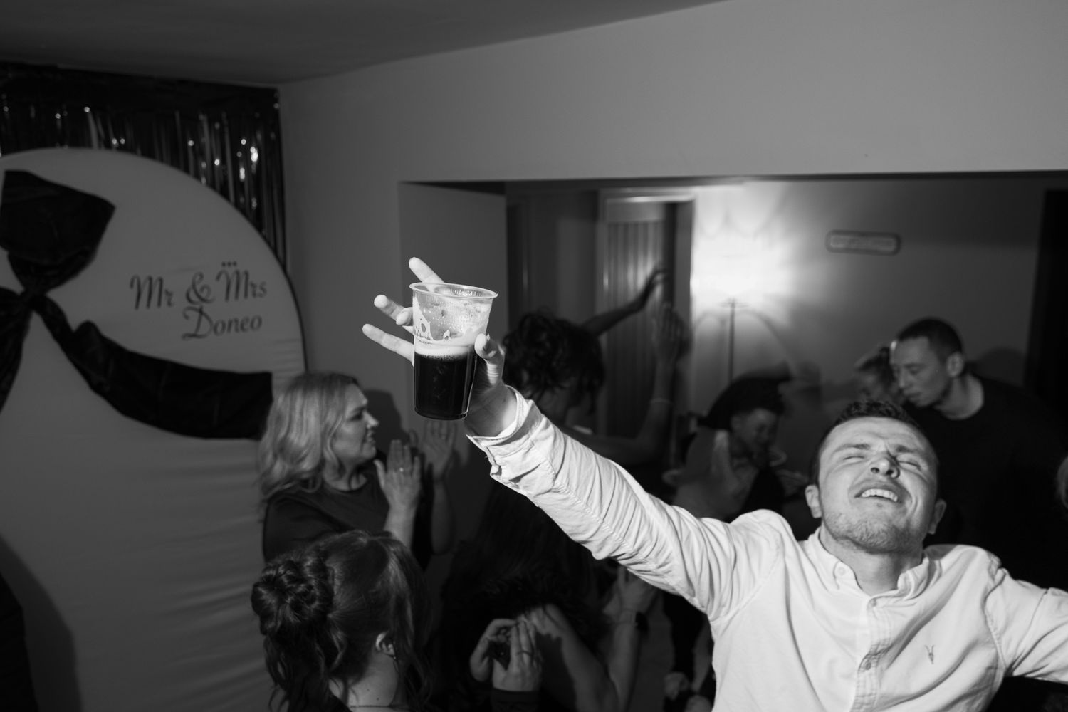 People dancing with arms raised in celebration at a dark indoor party venue.