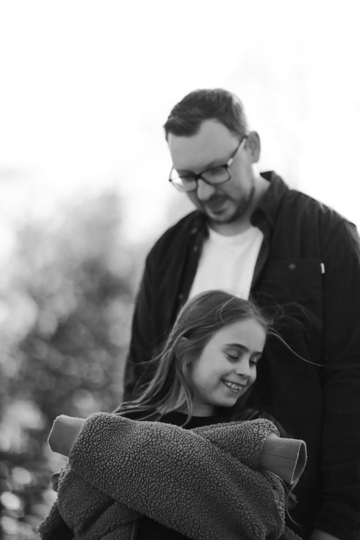 A tender black and white portrait of a couple sharing an intimate moment outdoors with soft bokeh in the background.