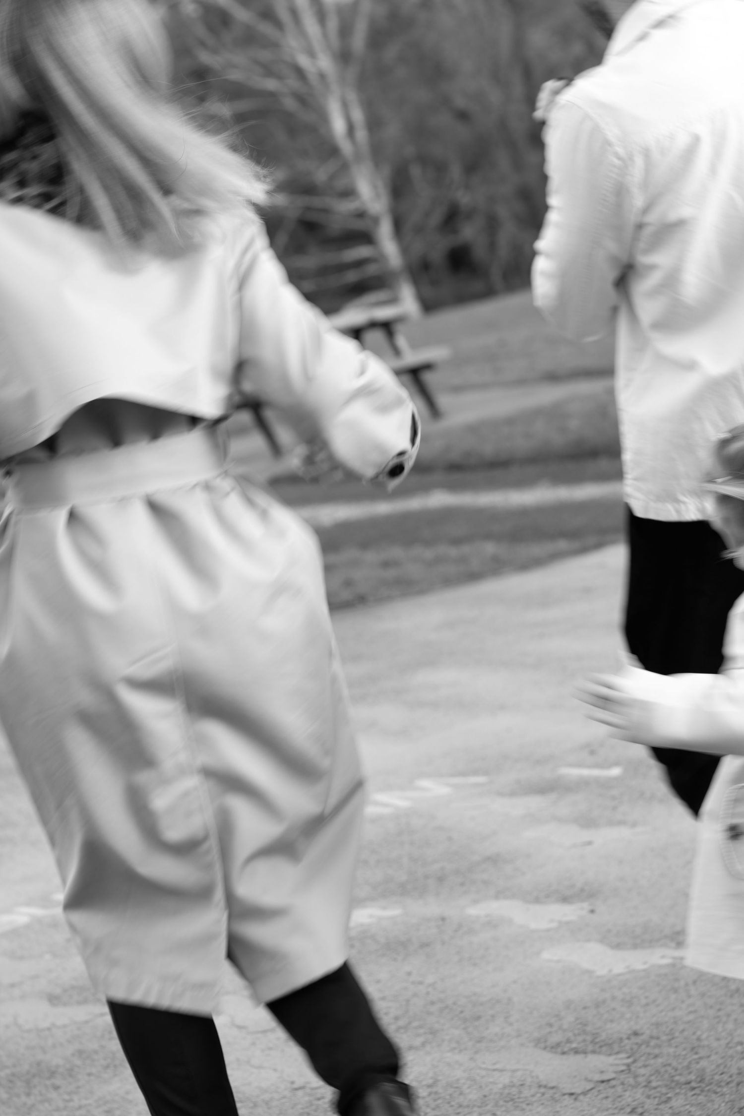 Motion blur sequence of someone in white clothing moving across a path outdoors.
