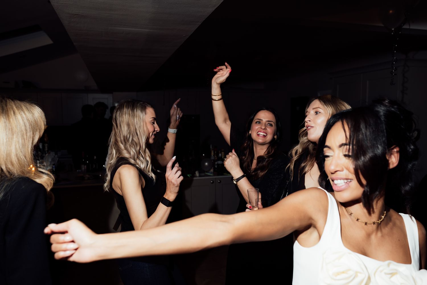 People dancing and celebrating at a lively party in a dark indoor venue.