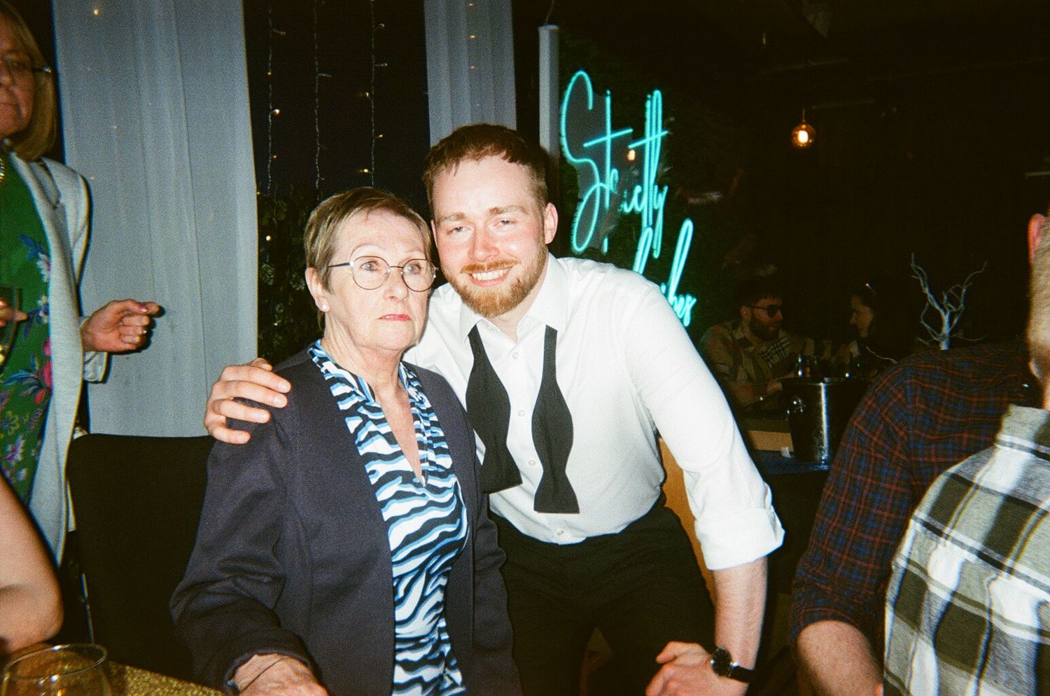 A group of people celebrating at a party with festive lighting and decor in the background.