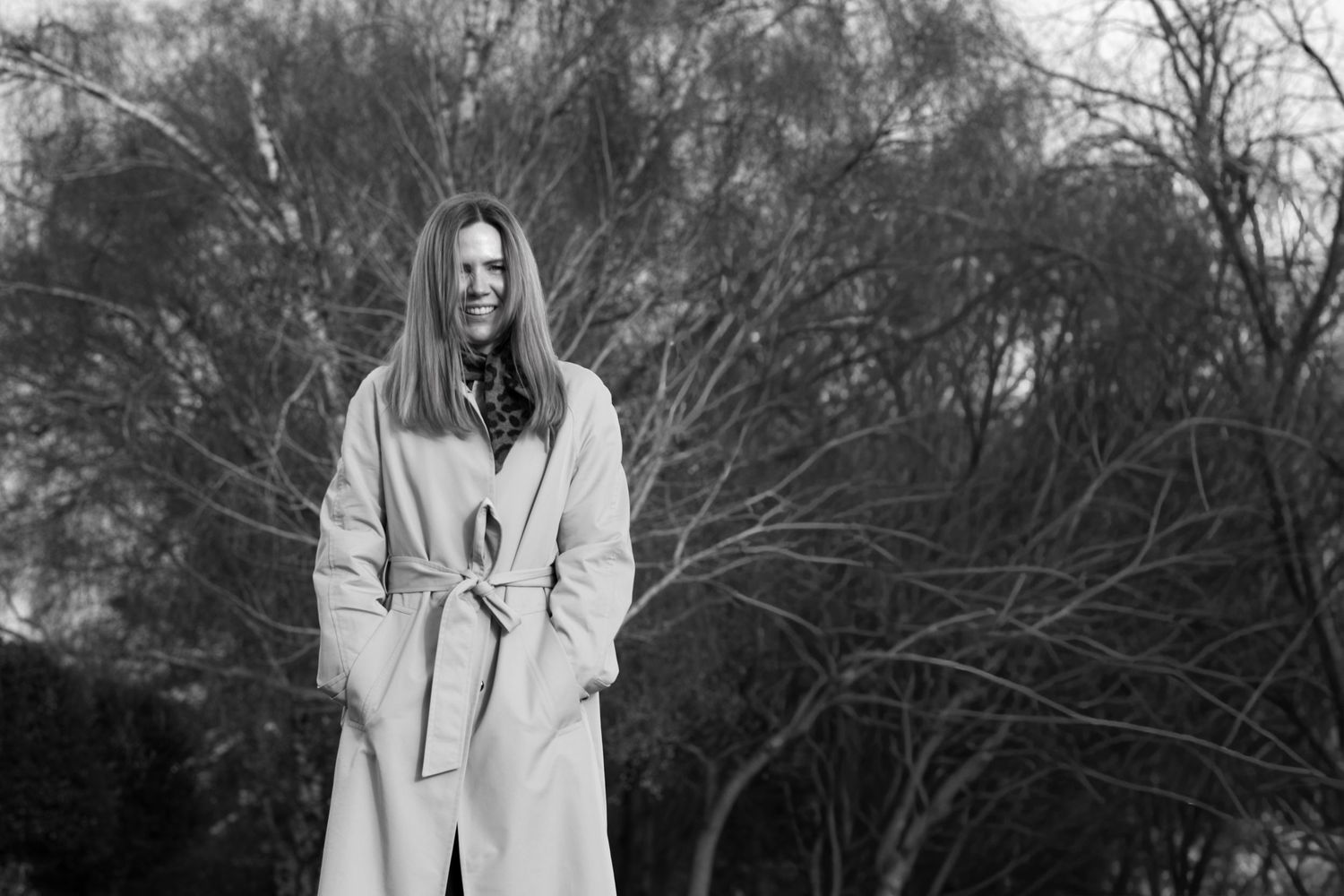 A sequence of black and white photos showing a person in a white coat standing among bare winter trees.