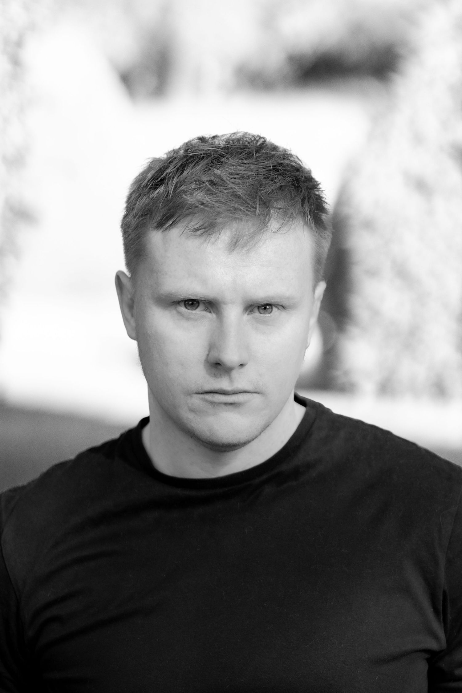 A black and white portrait photo series showing the same person in different poses wearing a black shirt.