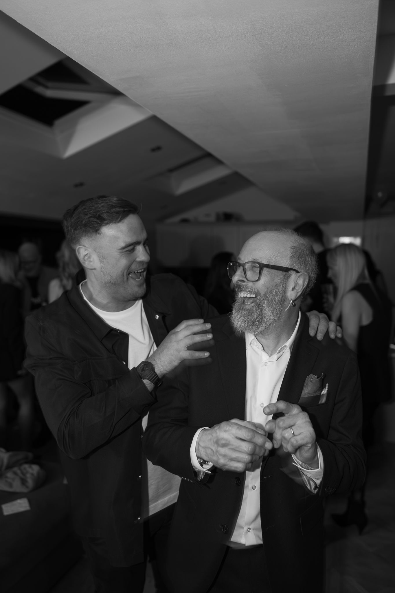 Men in formal attire engaged in animated conversation at an indoor event.