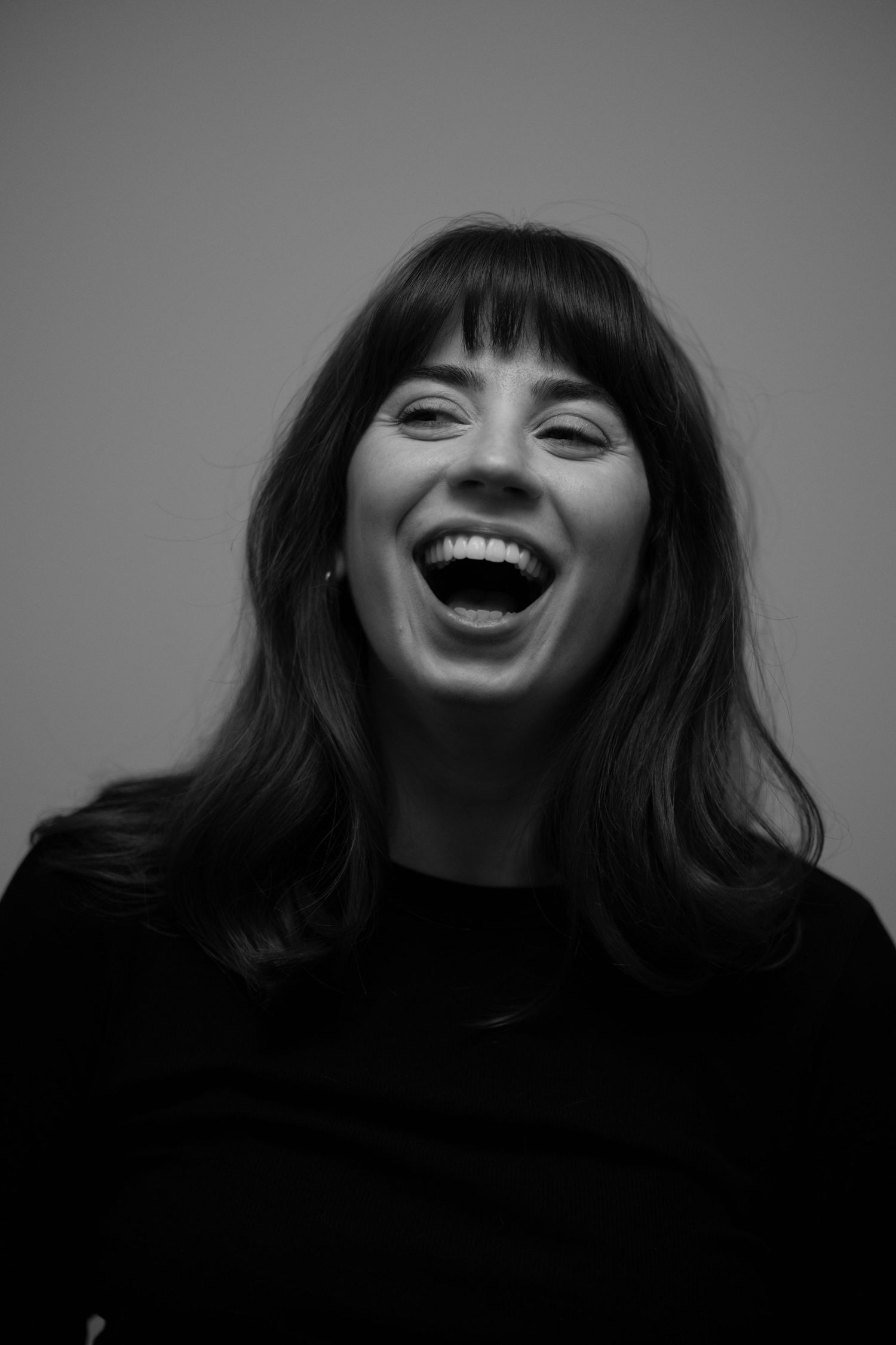 A series of black and white portraits showing joyful expressions and laughter against a dark background.