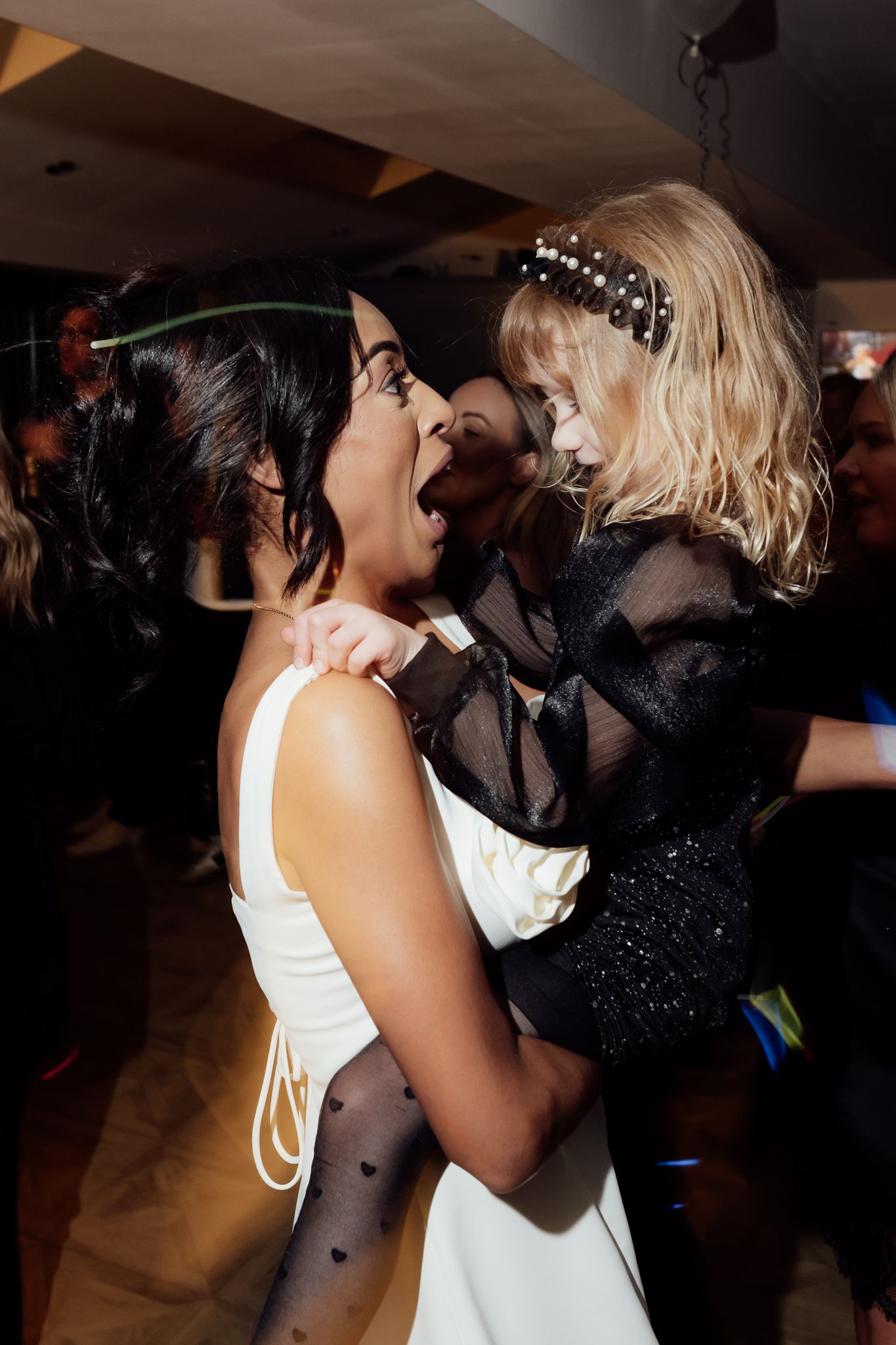 Partygoers dancing together in a dark room with atmospheric lighting.