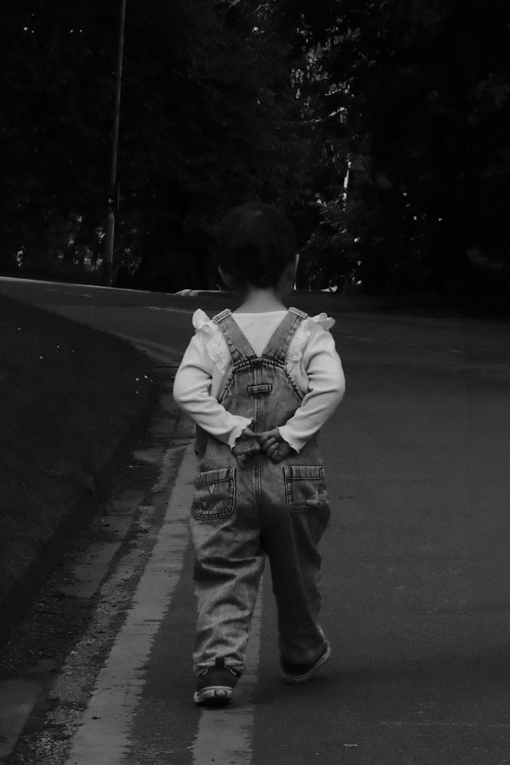 Black and white sequence of a person in denim overalls walking down a path in four progressive frames.