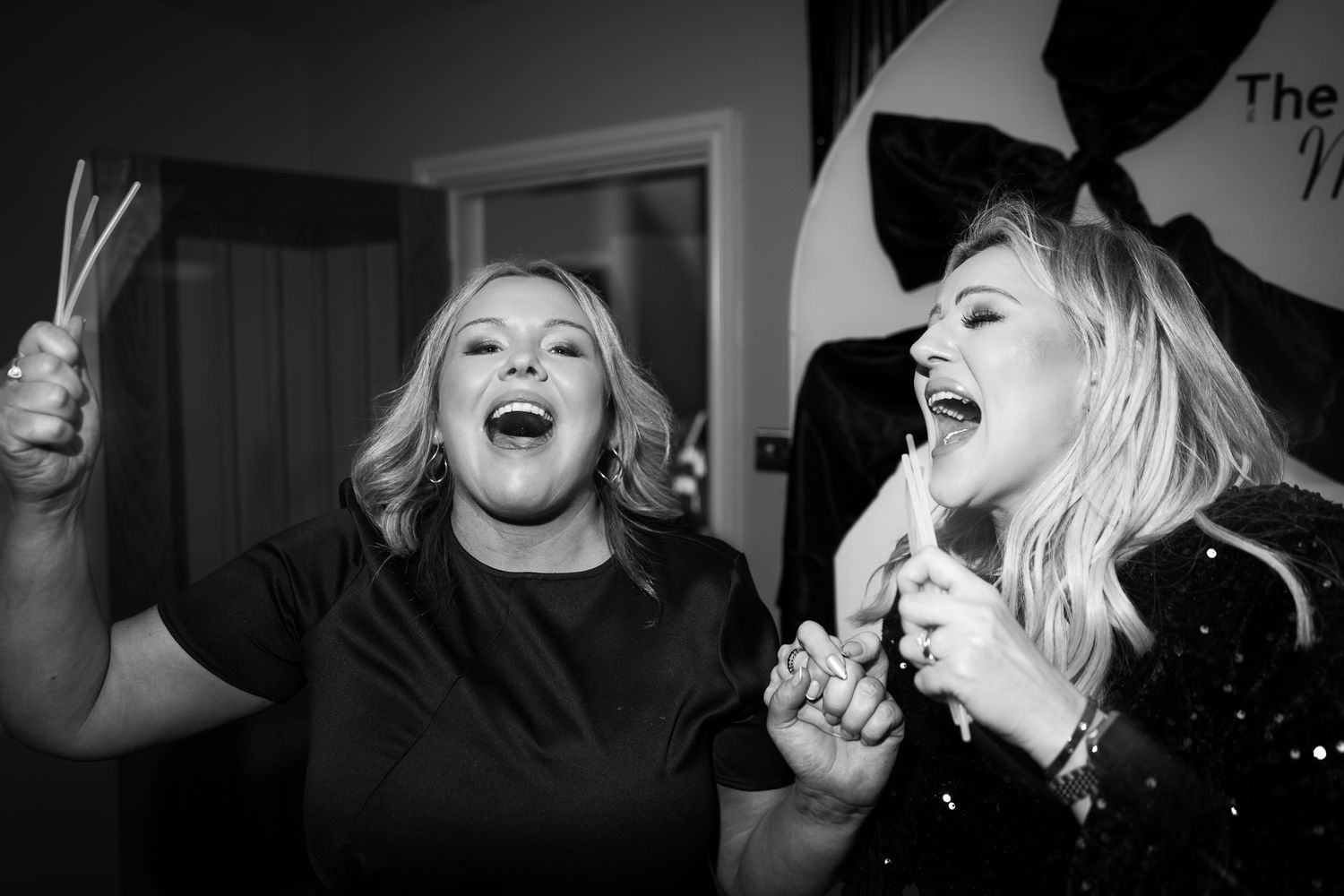 Group of party guests laughing and making peace signs in a candid nighttime celebration shot.