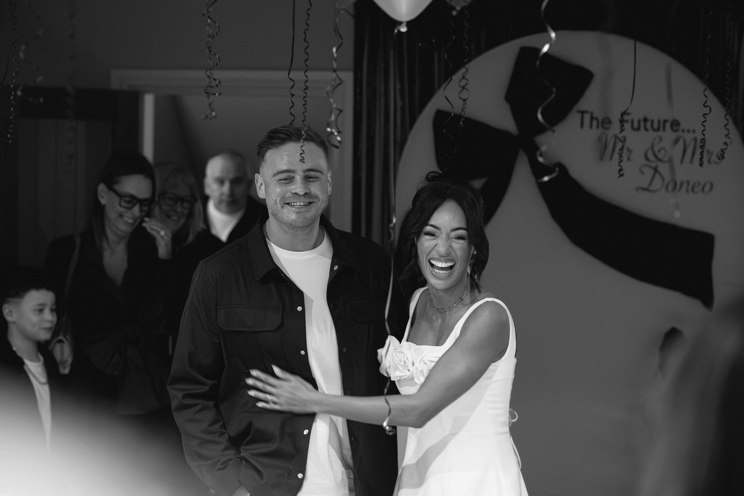 Black and white photo of people dancing and celebrating at a lively party.