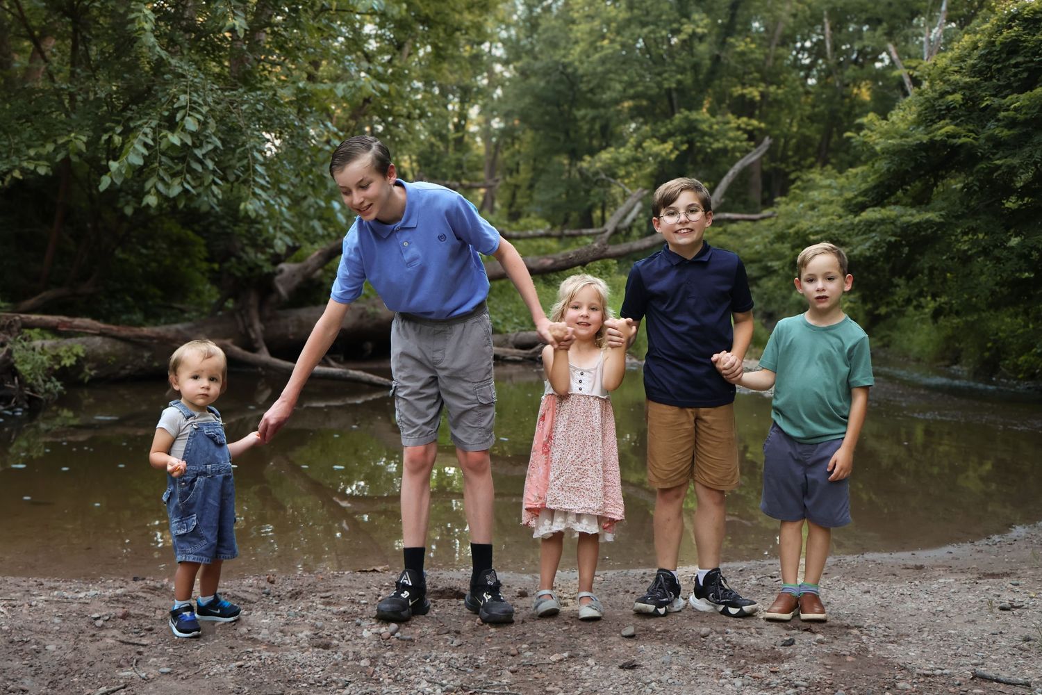 Family members lined up along a riverbank for a casual outdoor photo.