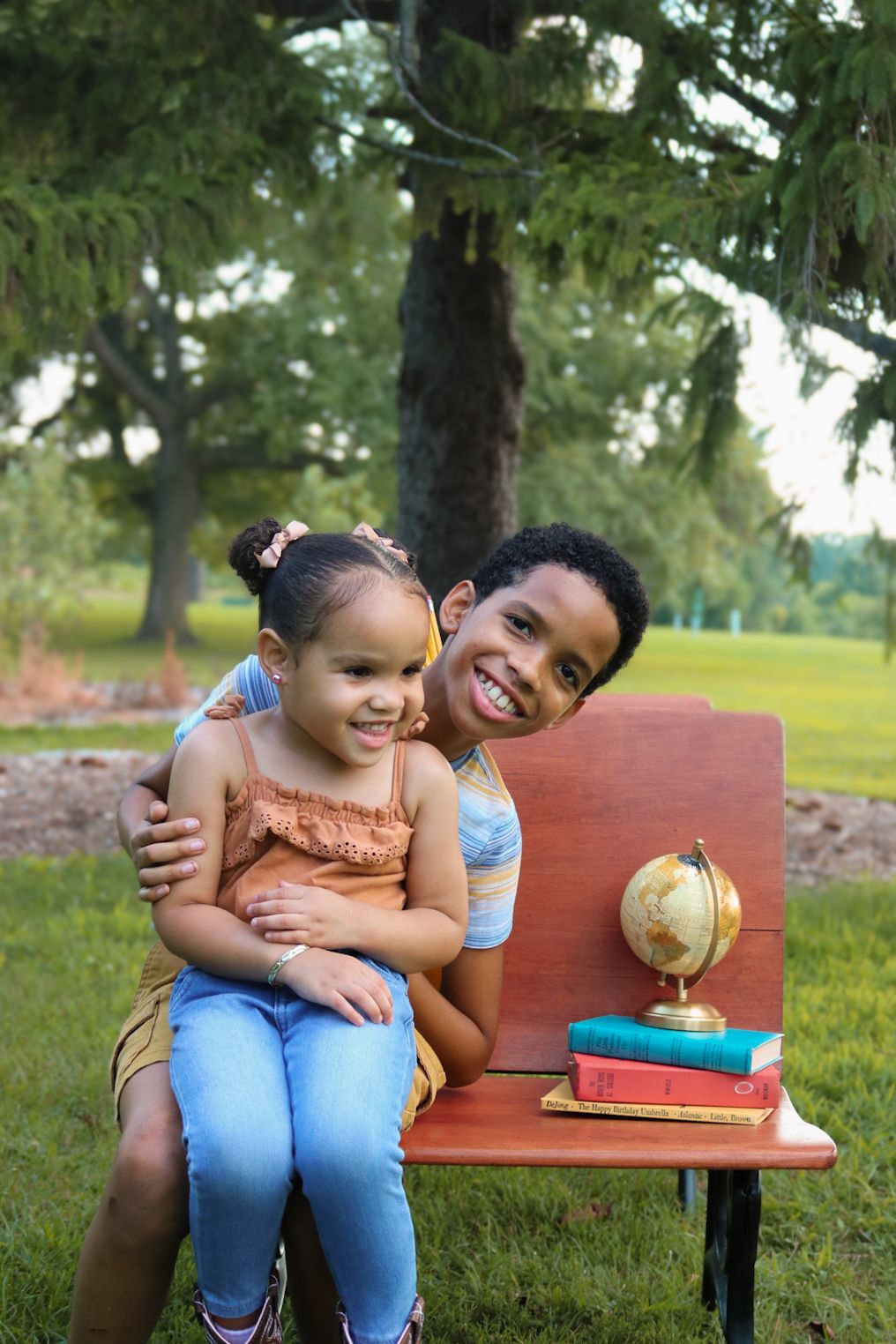 Family members sharing a tender moment while reading together on a wooden bench in a park.