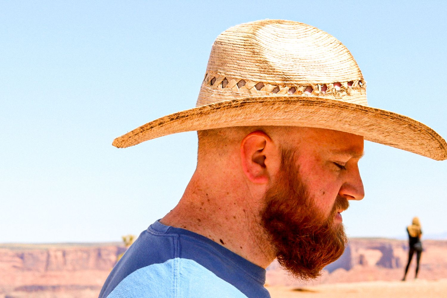 Person wearing a straw hat looking out over desert canyon landscapes.