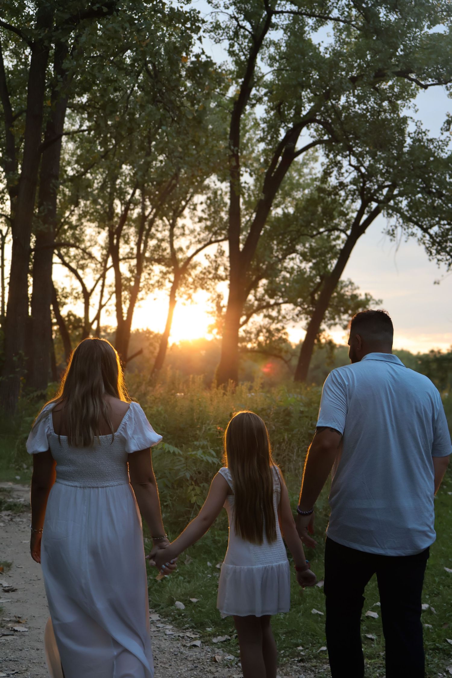 Silhouettes of people walking together at sunset against a backdrop of trees.