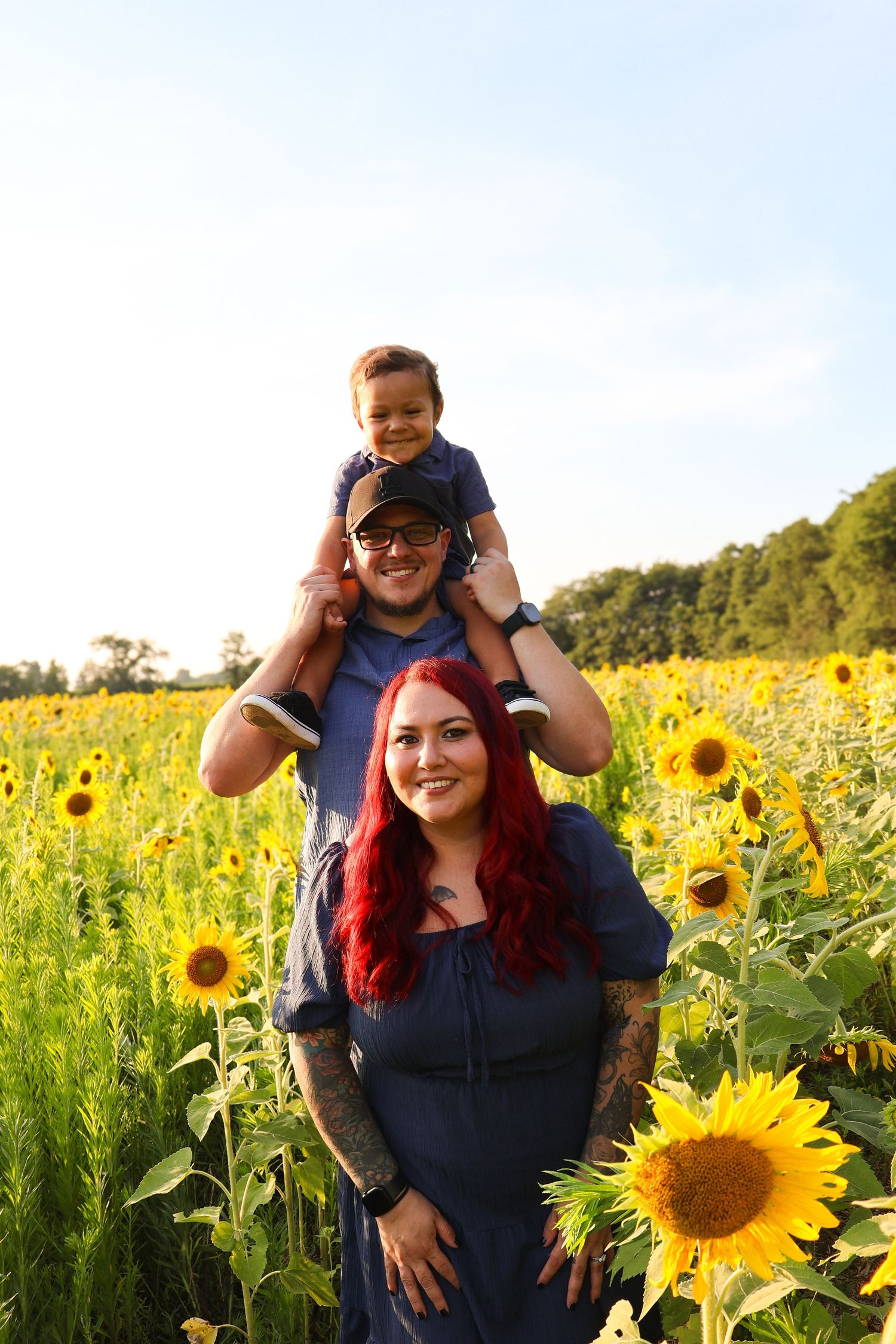 A cheerful group poses in a vibrant sunflower field during golden hour.