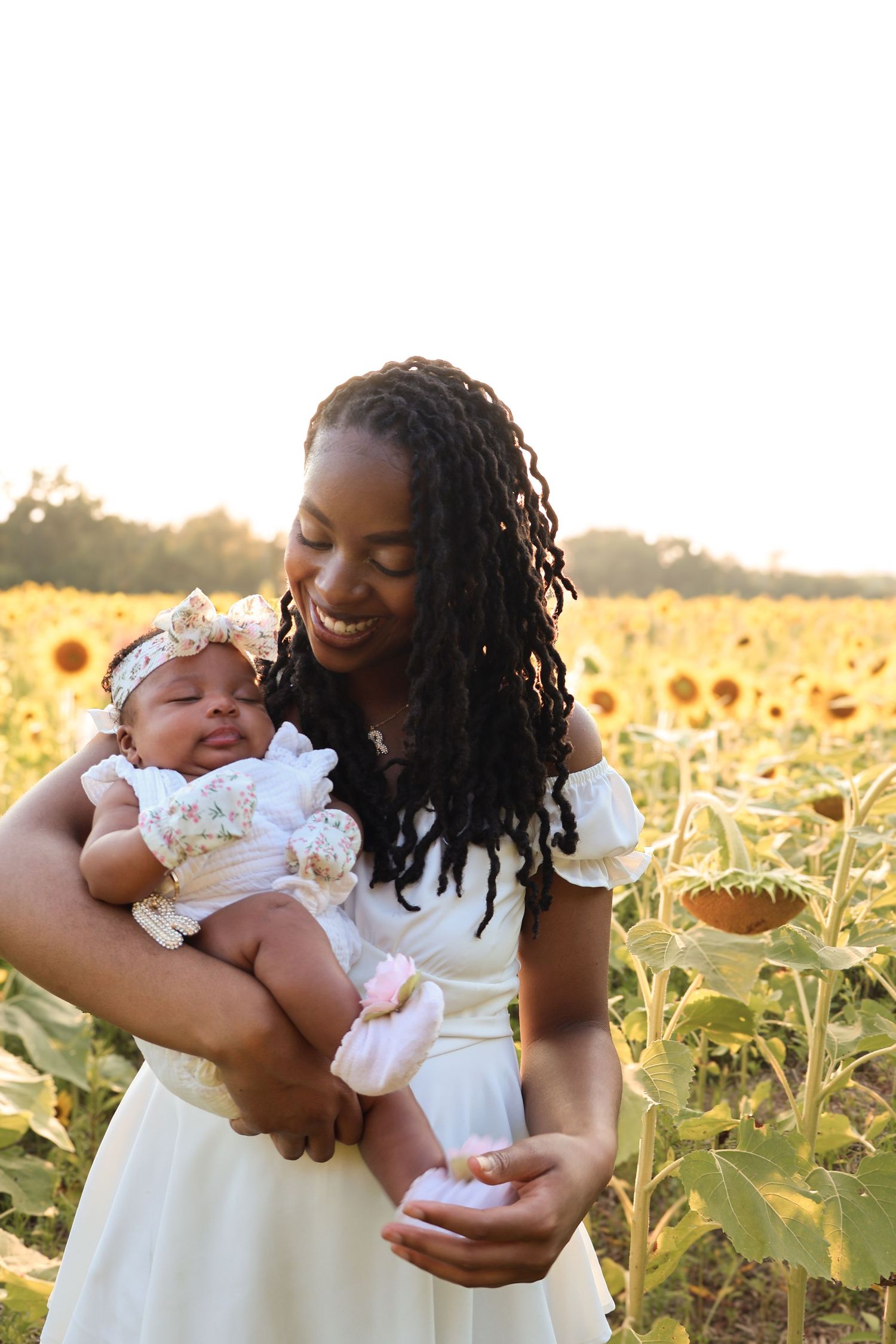 Mother and child sharing joyful moments in a sunflower field at sunset.