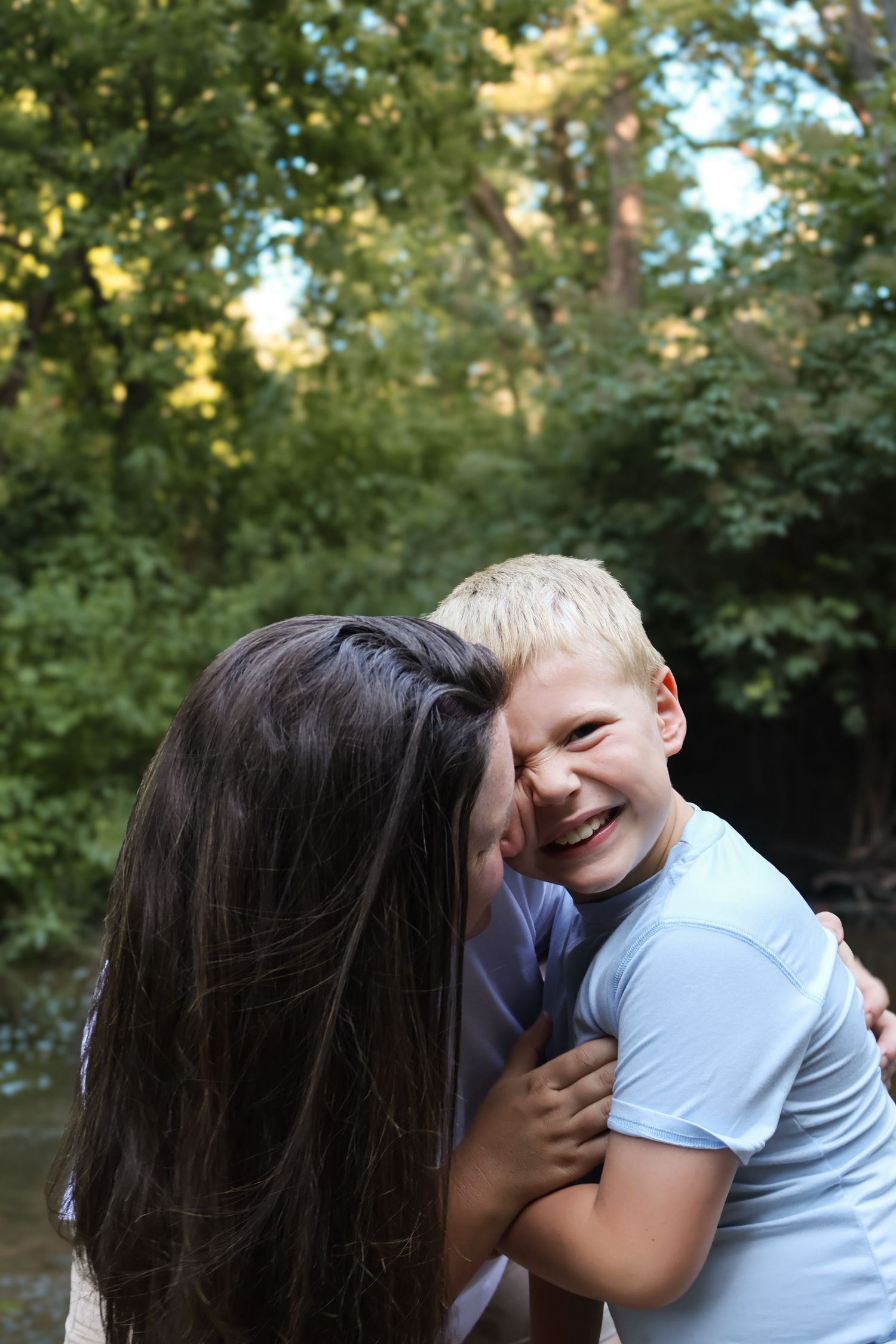 Candid moments of family affection captured in outdoor setting.