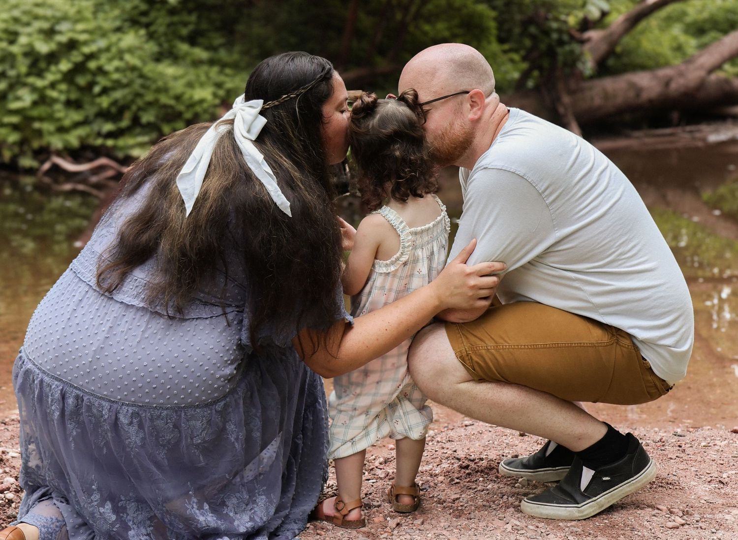 Couple sitting together on rocks by a creek sharing an intimate moment.
