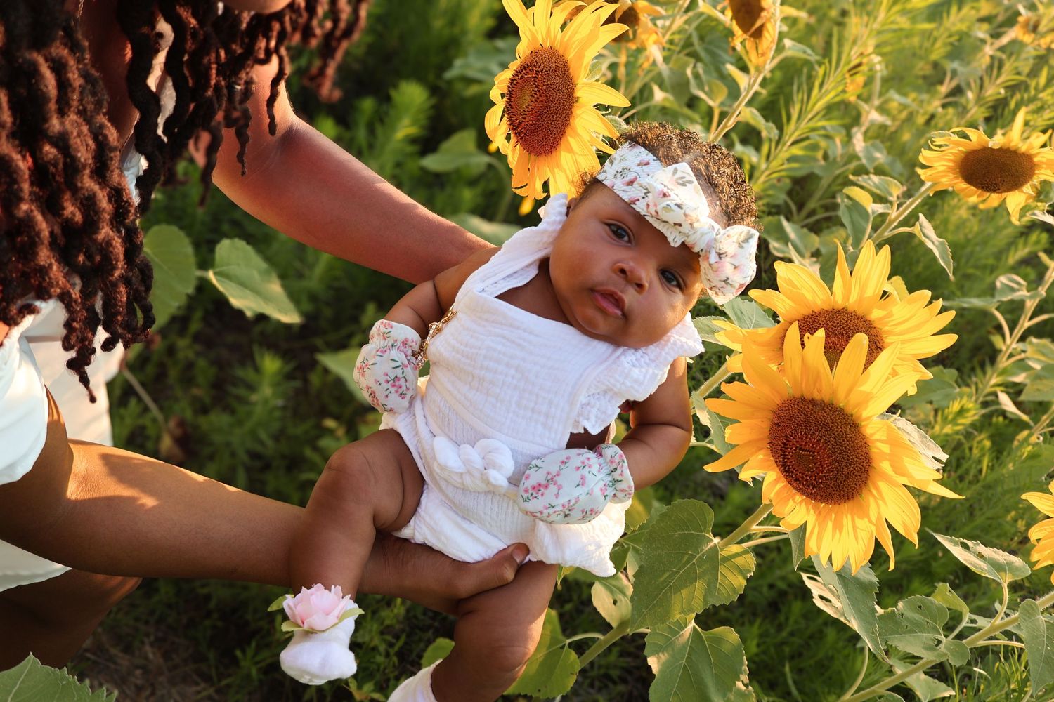 Close-up details of white dresses against sunflower field background.