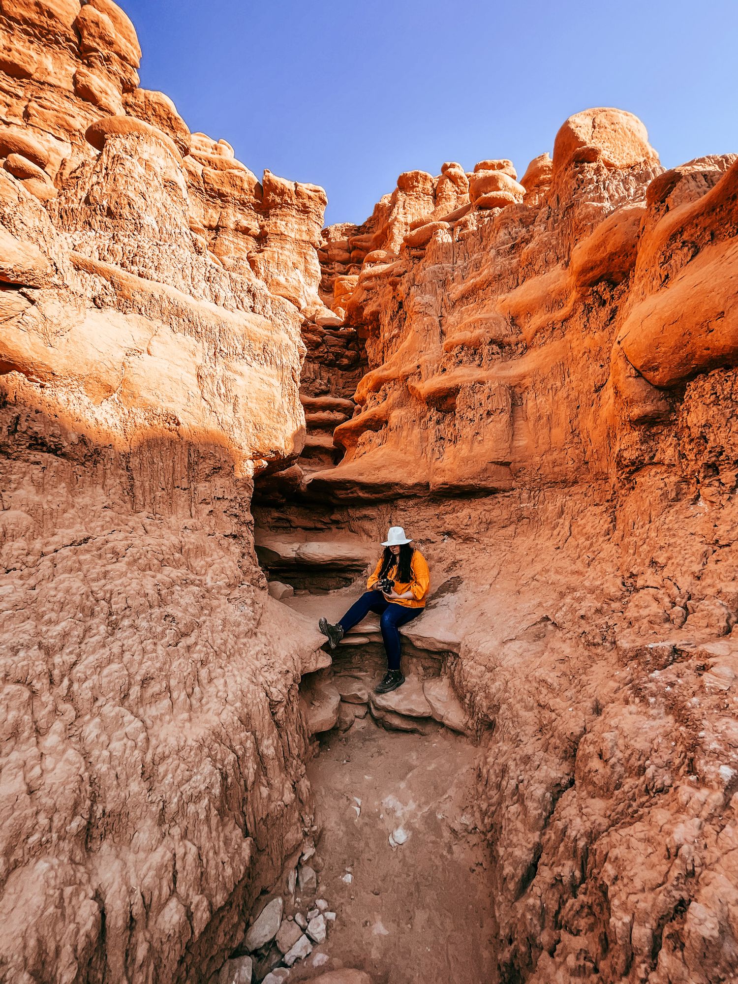 Red rock canyon formations with steep walls and narrow passages in a desert landscape.