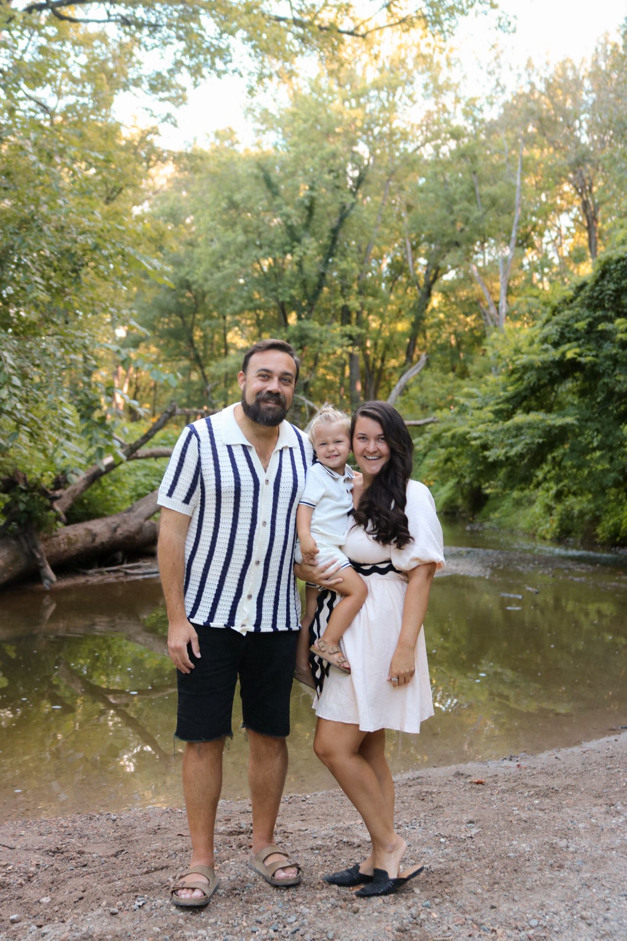 A couple poses playfully by a creek wearing coordinated black and white outfits.
