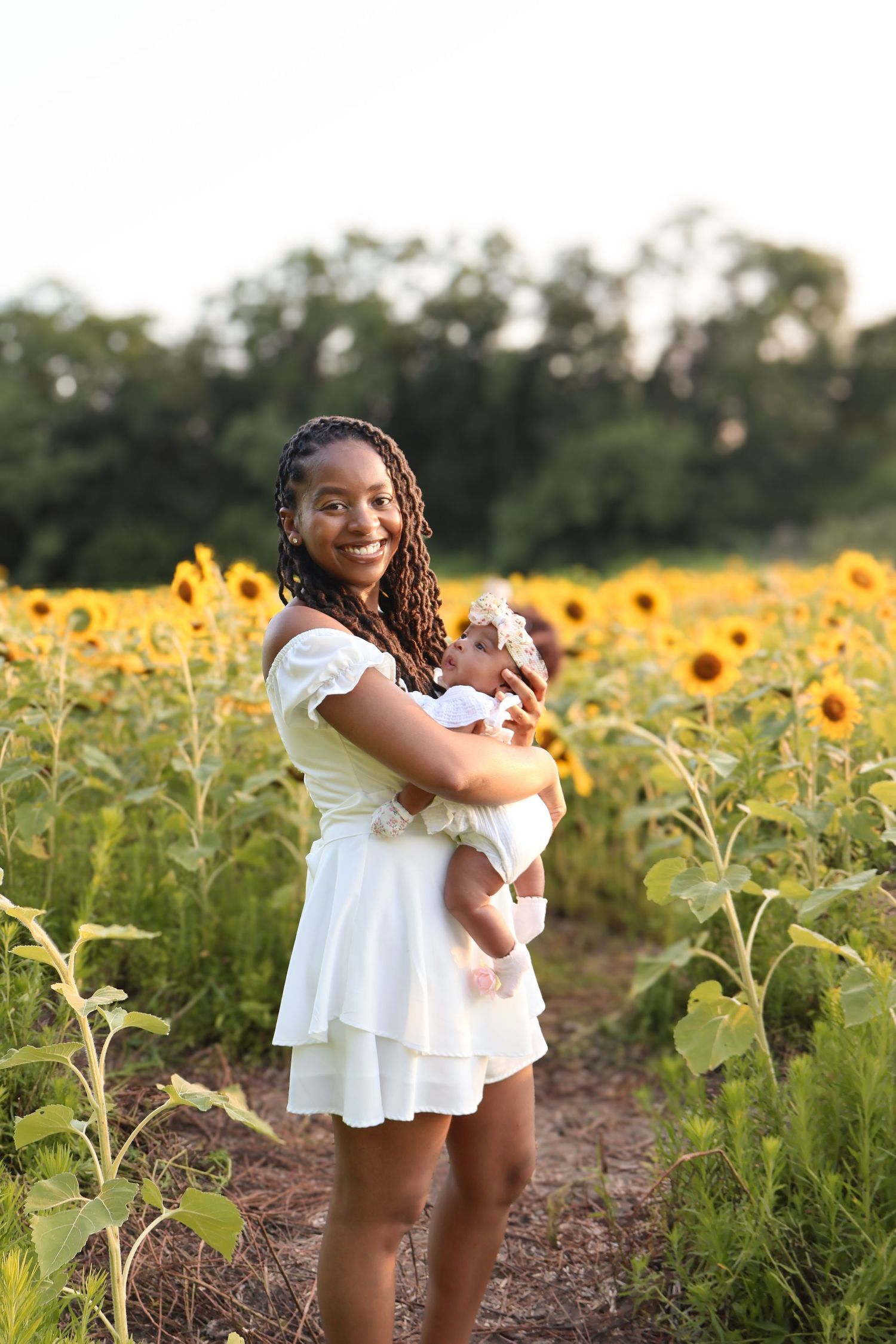 Mother and baby sharing tender moments among blooming sunflowers.