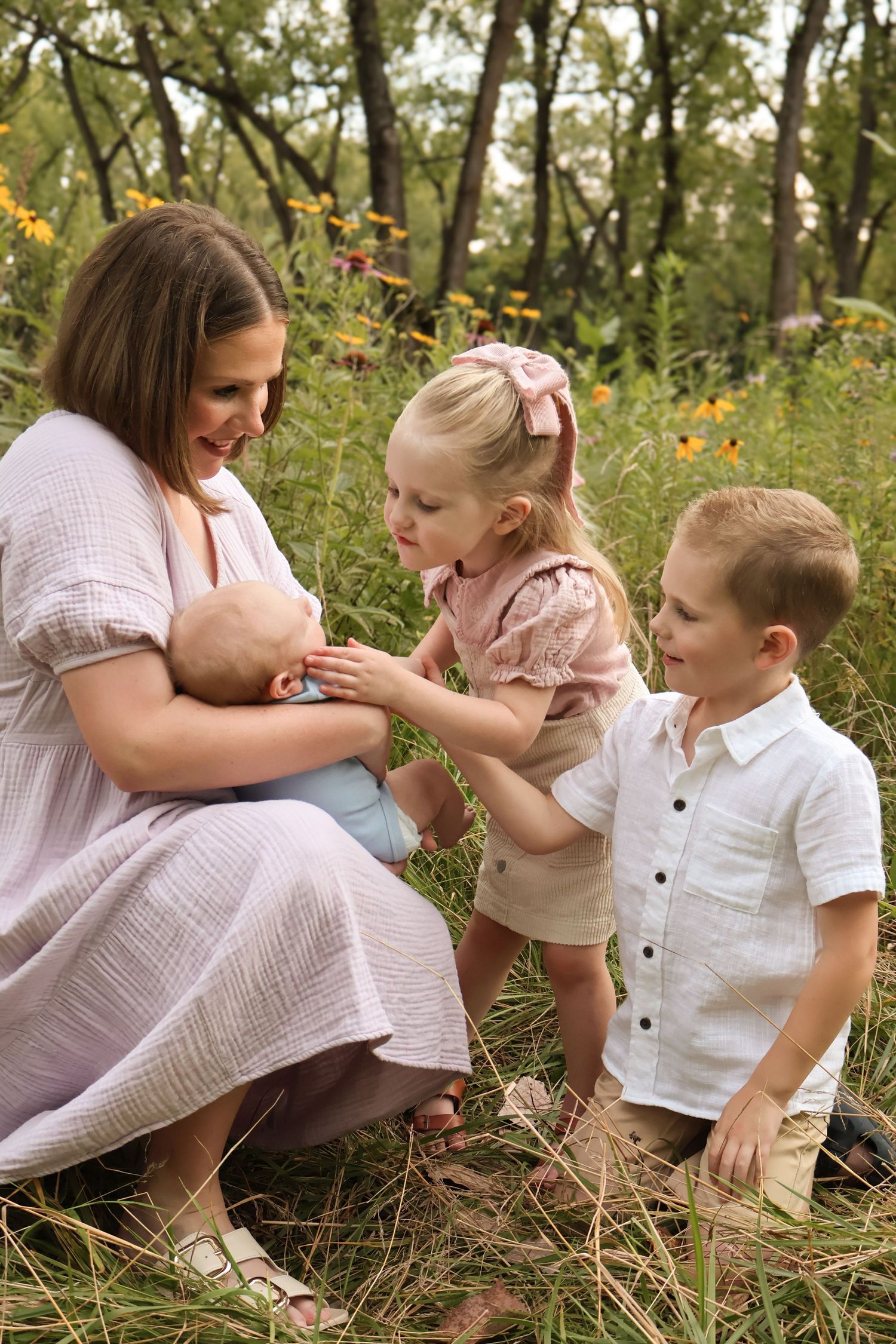 Family sitting together on grass having tender interactions in a natural outdoor setting.