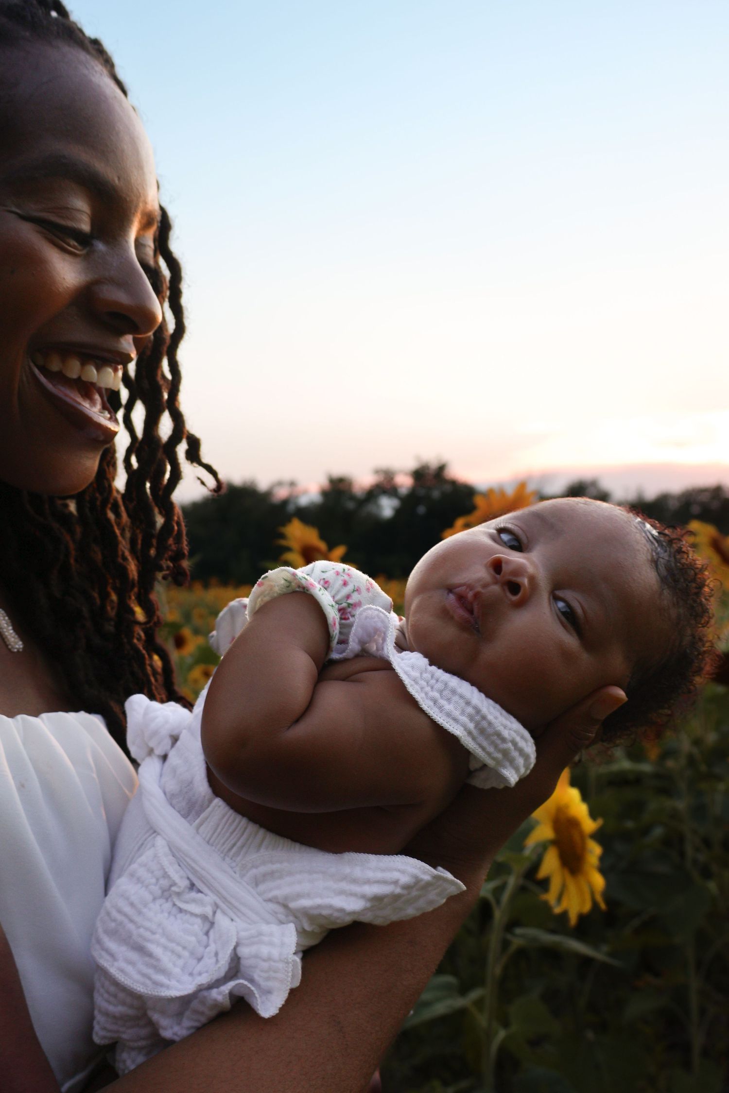 Sweet moments between parent and baby captured in a sunflower field during golden hour.