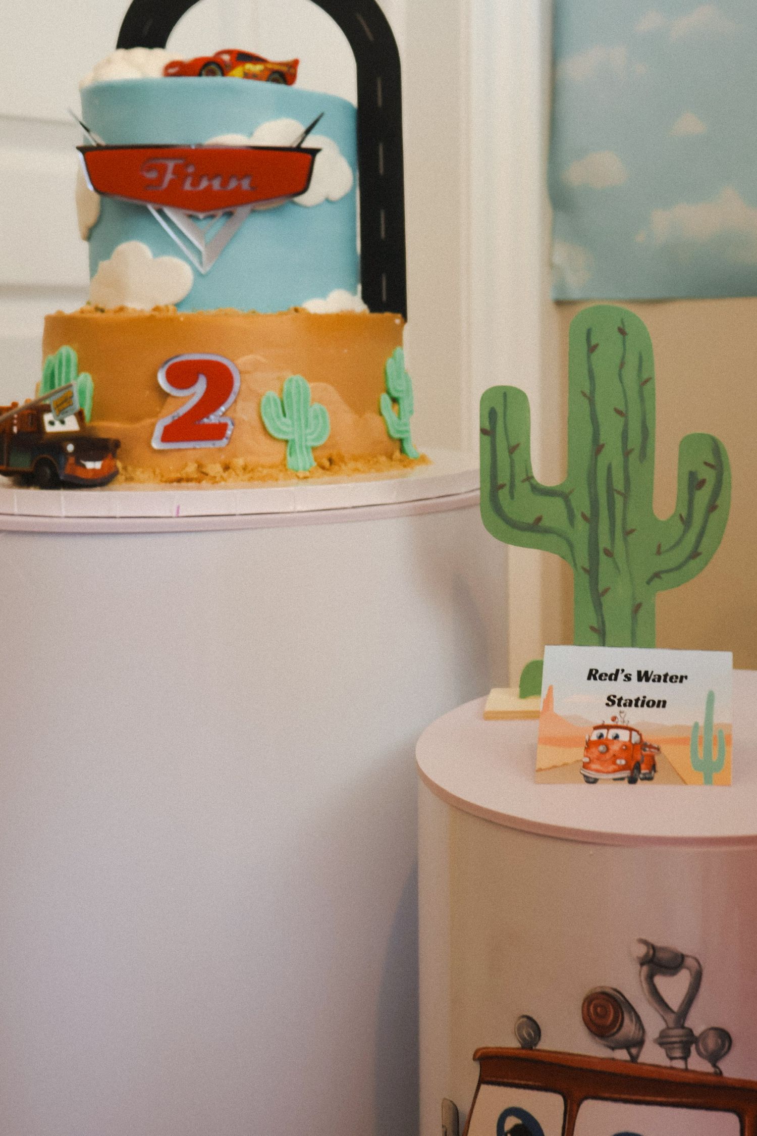 Desert-themed birthday cake with cactus decorations and racing elements.
