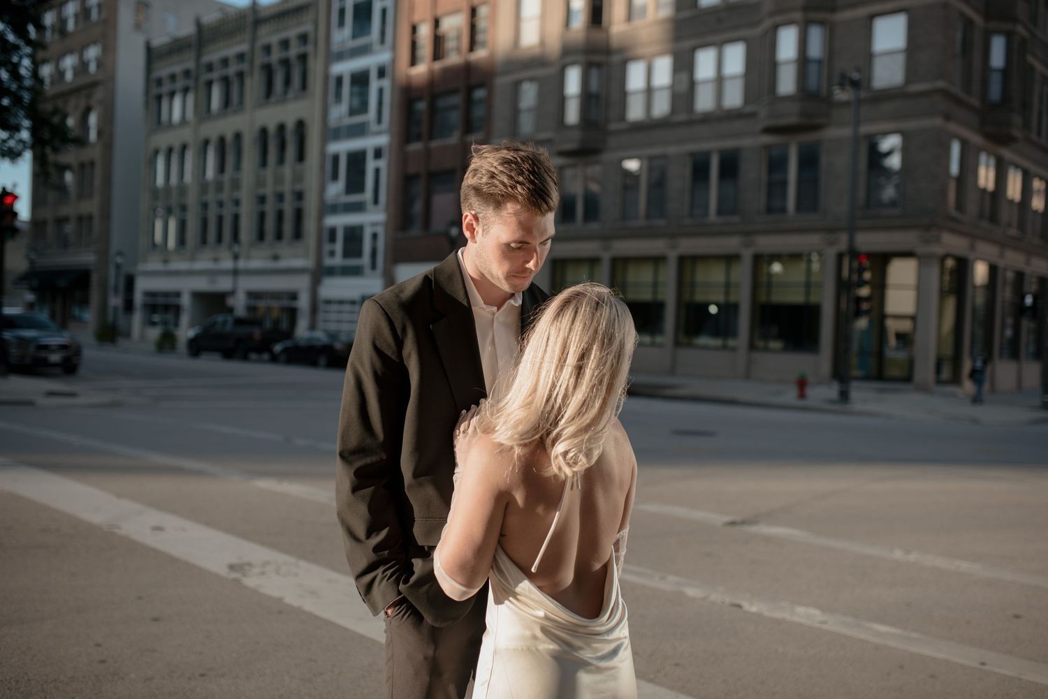 Evening street photography of couple in formal wear sharing intimate moment downtown.