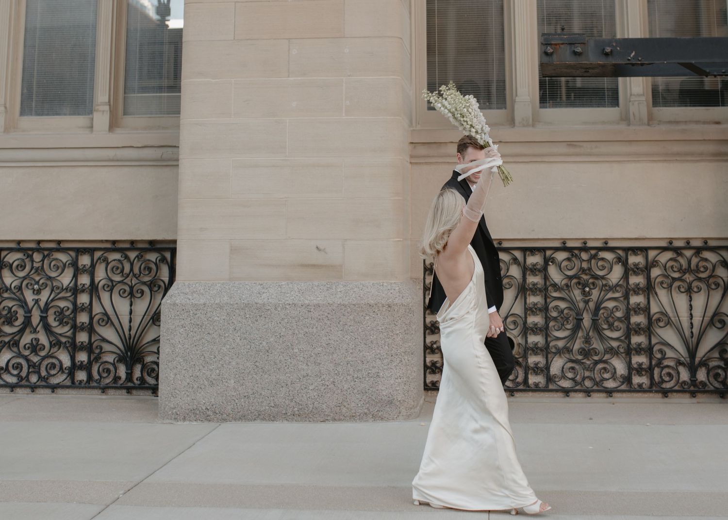 Elegant wedding photos captured outside a classical stone building with ornate railings.