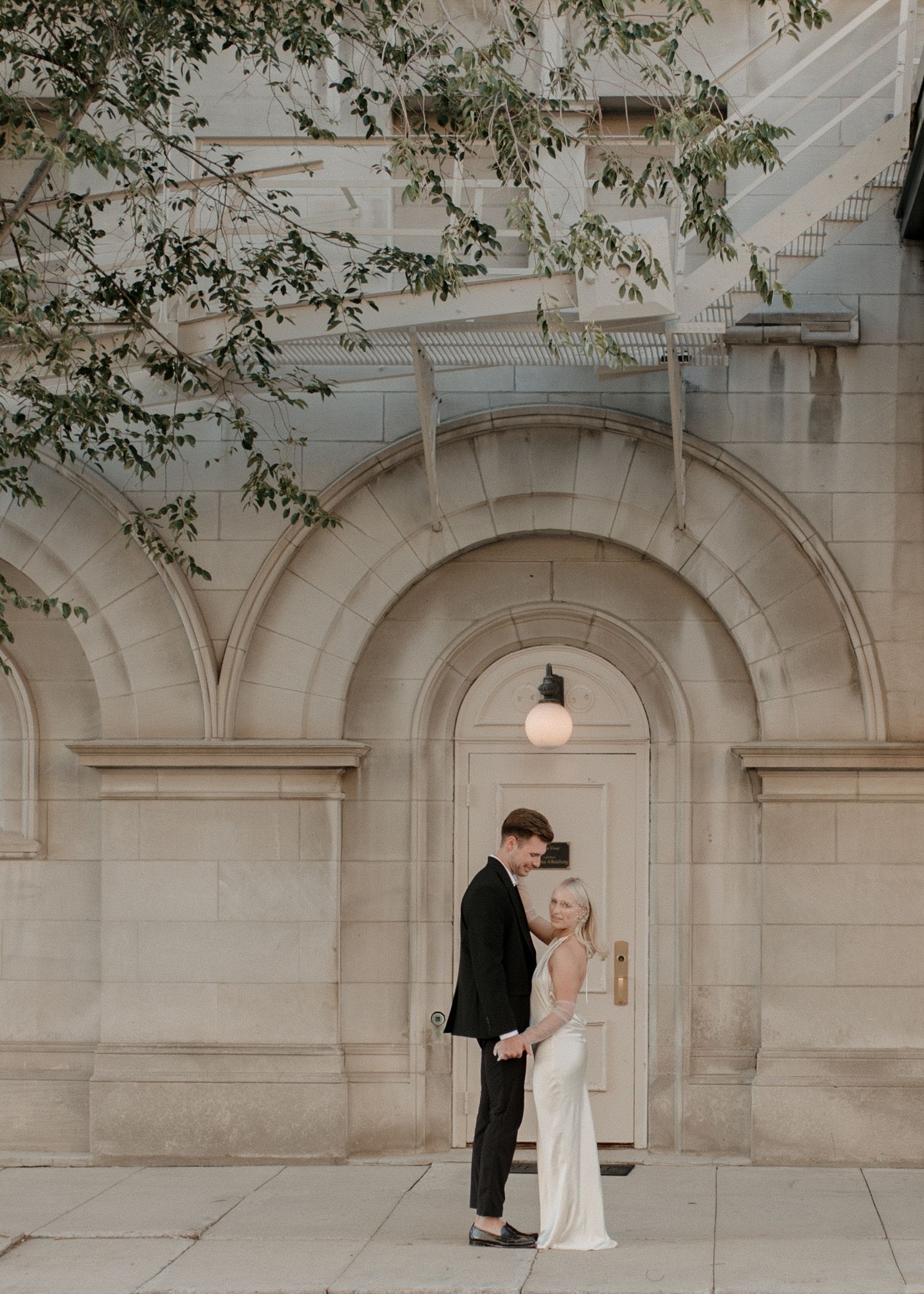 An elegant stone archway forms the backdrop for a stylish wedding photography session.
