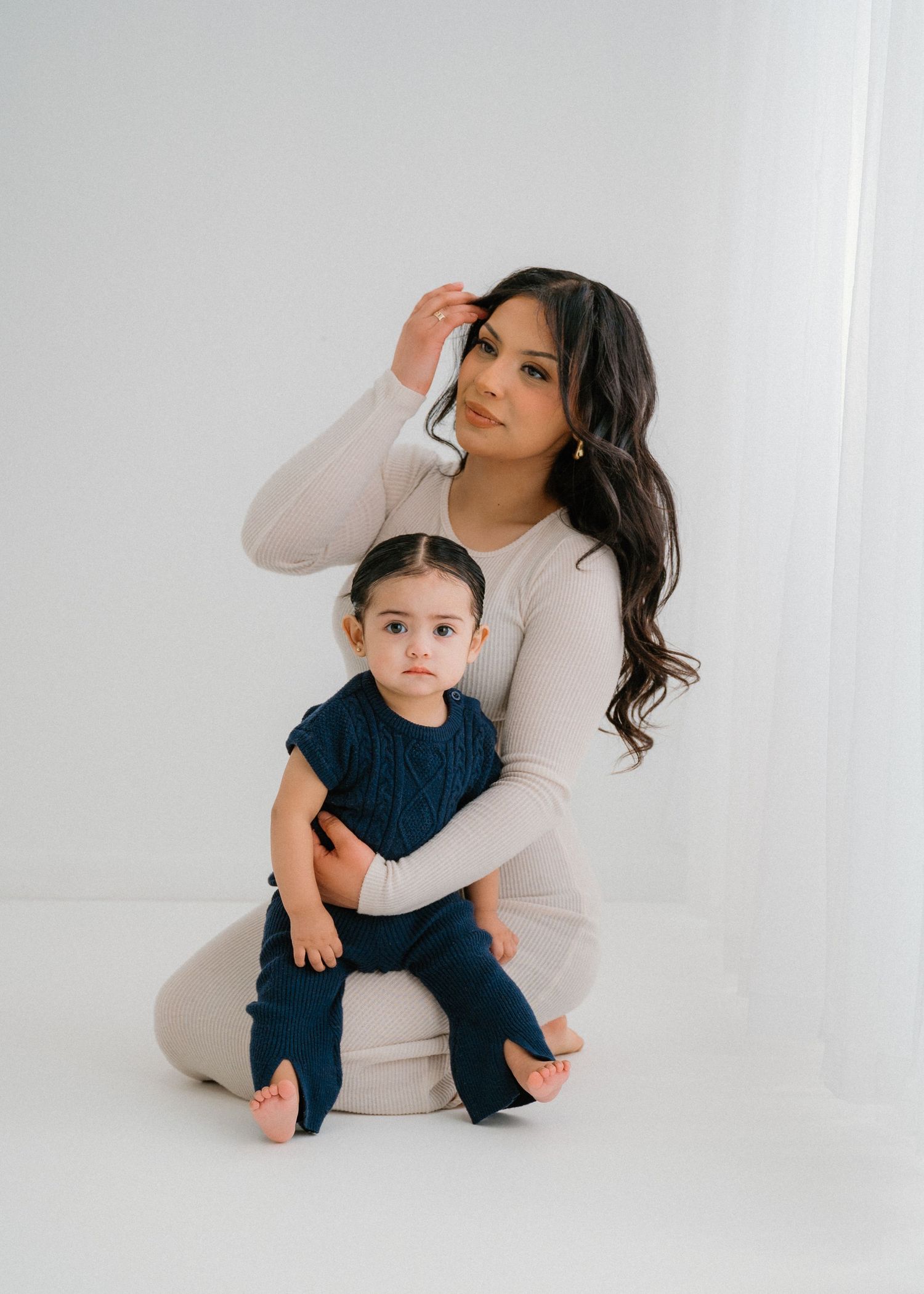 Family members in casual attire share loving moments against a stark white backdrop.