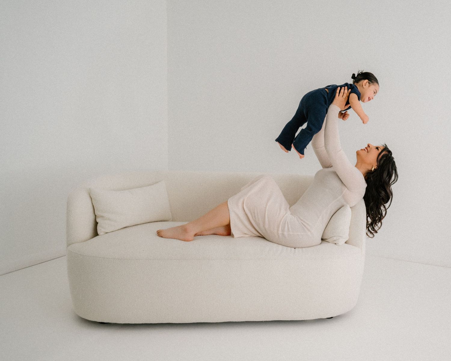 Minimalist photography series showing intimate family moments on a white chaise lounge.