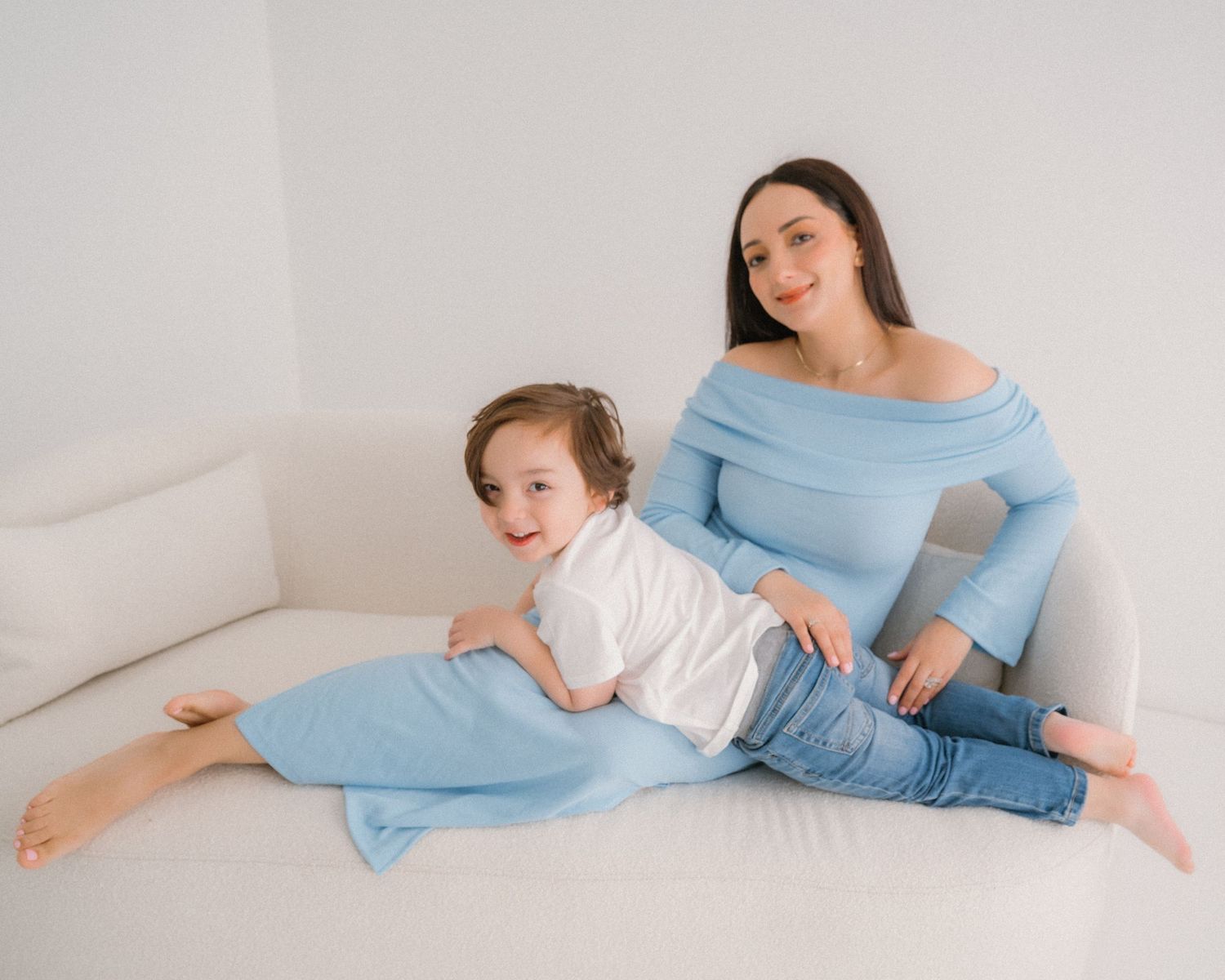 A family lies comfortably together on the floor in a minimalist white setting.