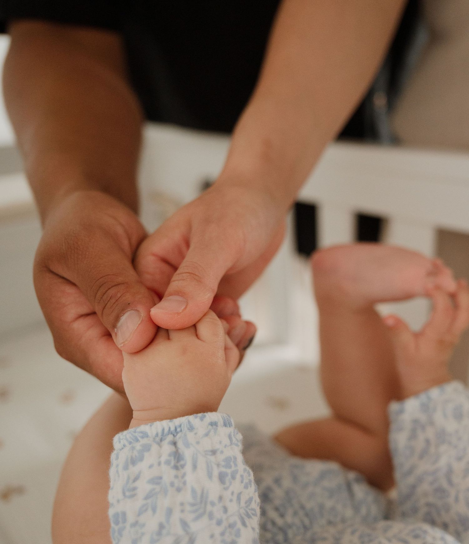 Close-up of hands gently massaging baby feet wrapped in blue floral fabric.