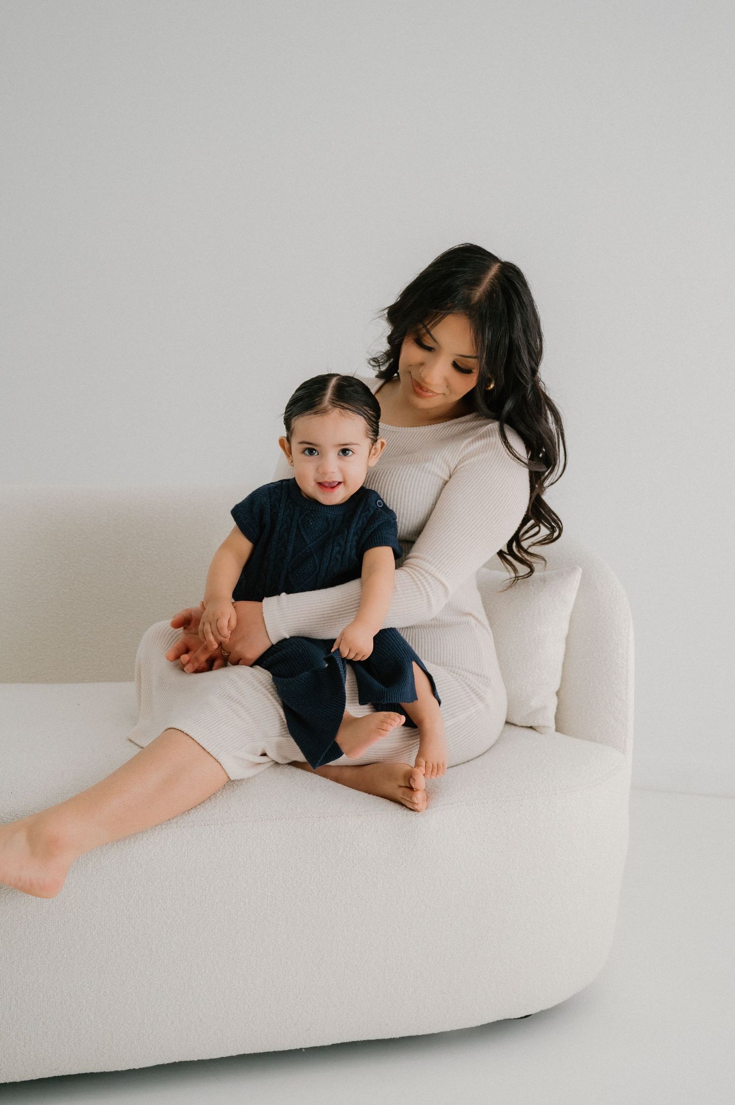 Parent and child share tender moments while relaxing on a white modern couch.